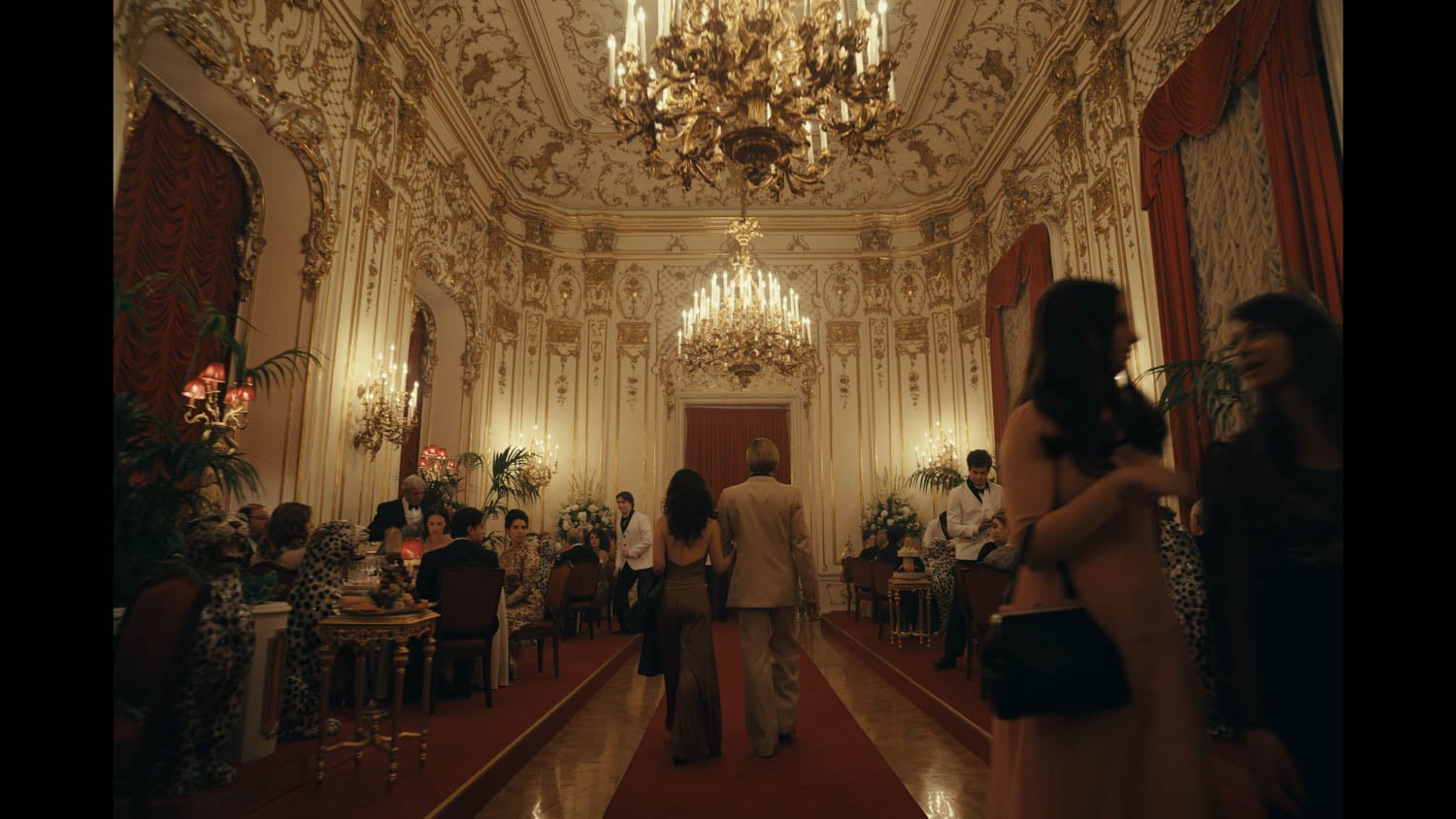Ornate ballroom with elegant chandeliers, gilded walls, and red drapes