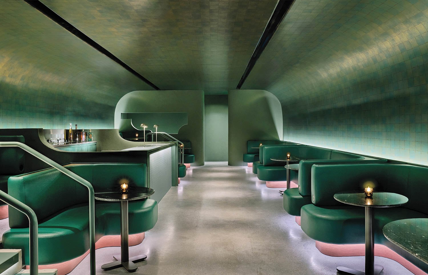 Sleek, modern bar with green leather booths and soft pink lighting