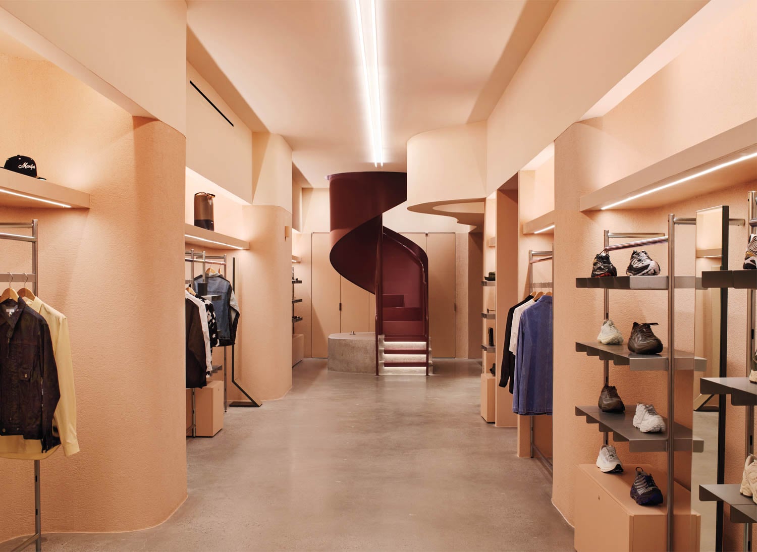 Stylish clothing store interior with soft peach walls, sleek shelves displaying shoes and jackets