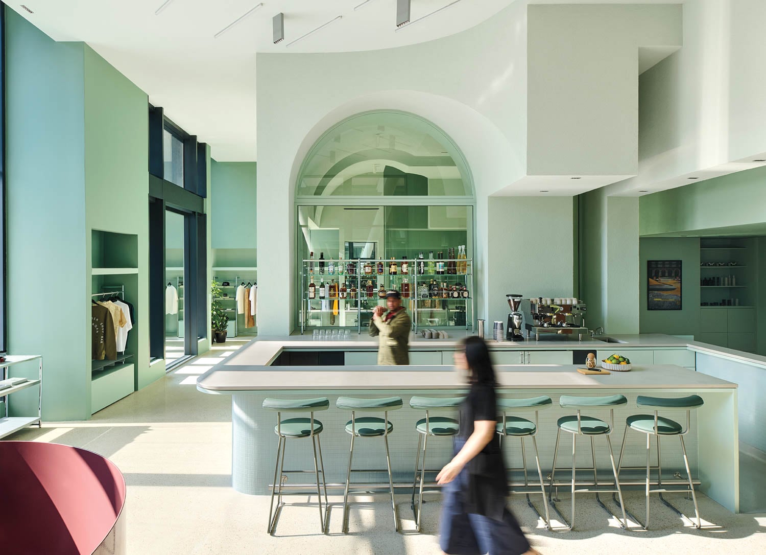 Spacious modern cafe-bar with mint green walls, minimalistic decor, and a large bar counter with stools