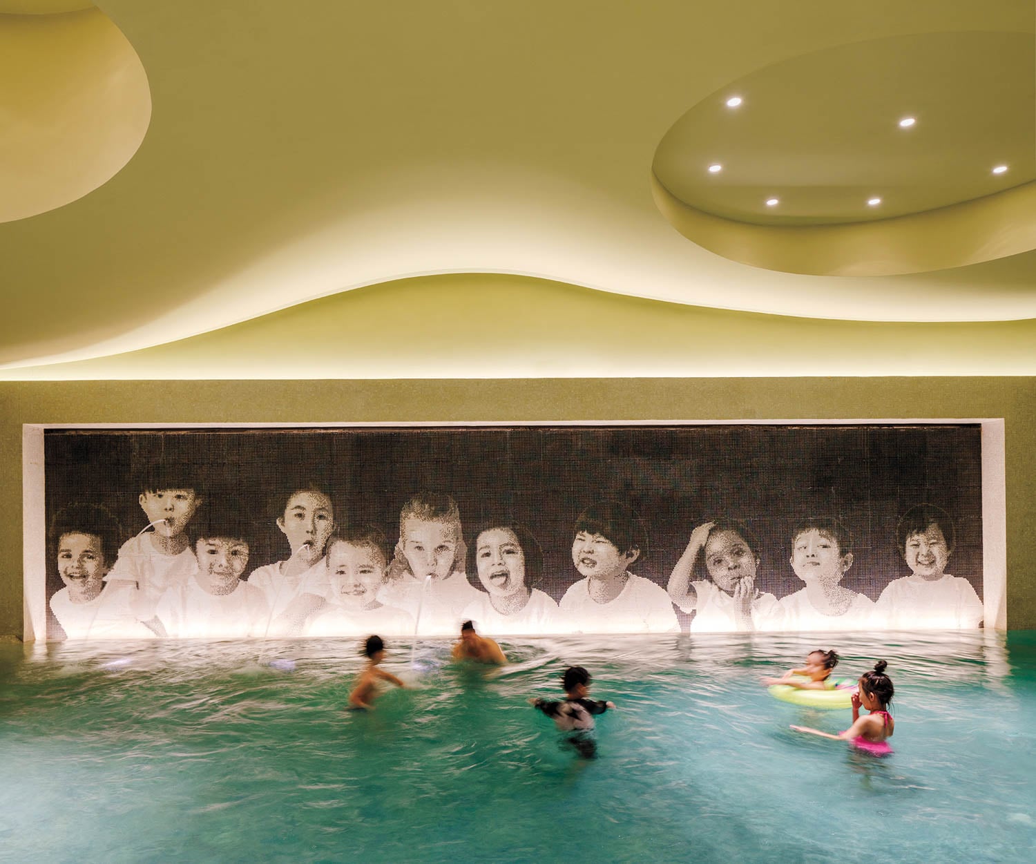 people swimming in pool in front of mural with children