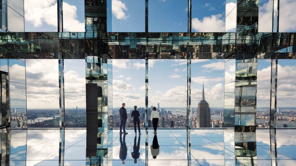 people standing by all glass windows overlooking city