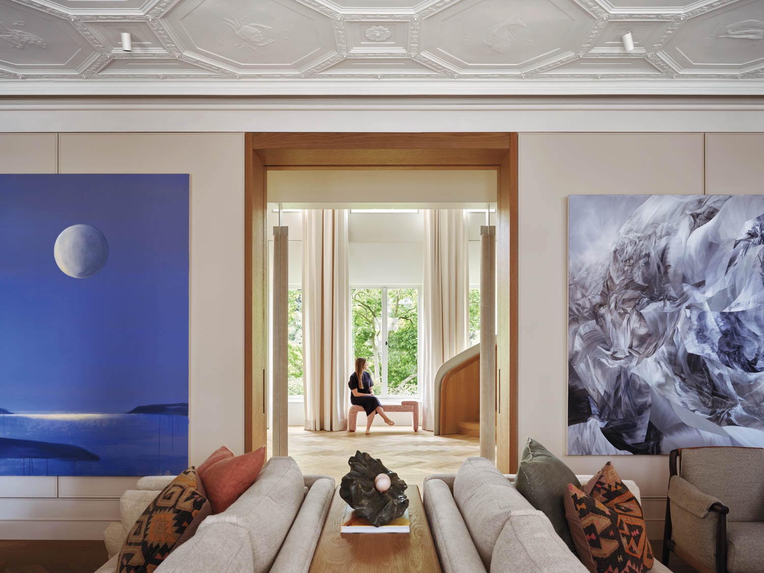 living room with artwork and view of person on bench