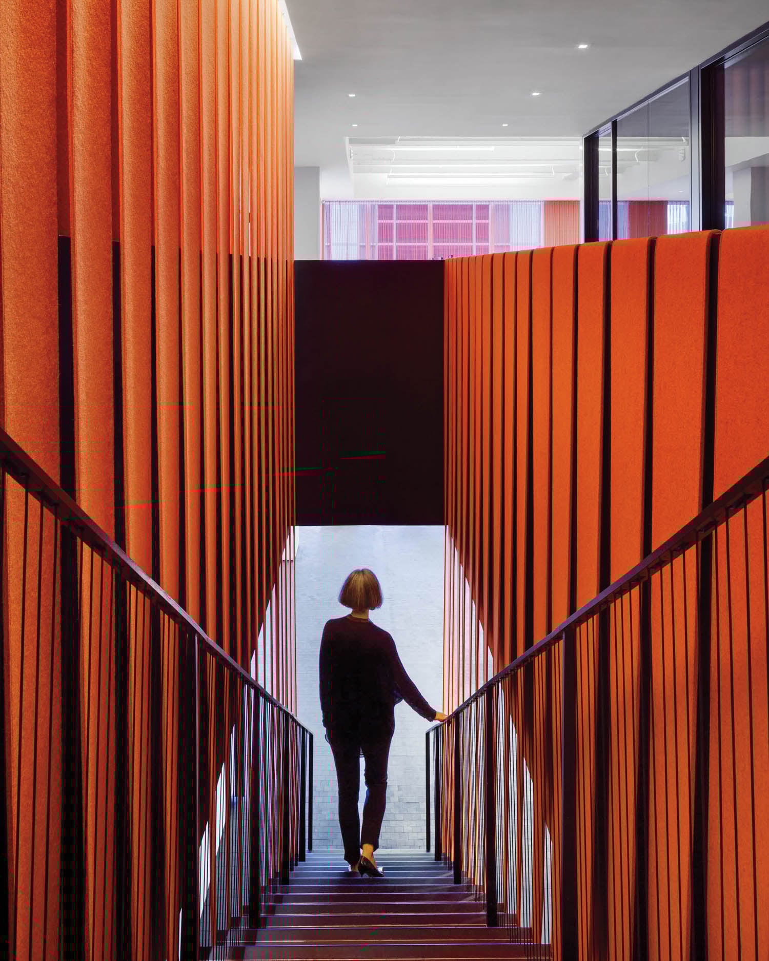 woman walking down staircase with orange drapes