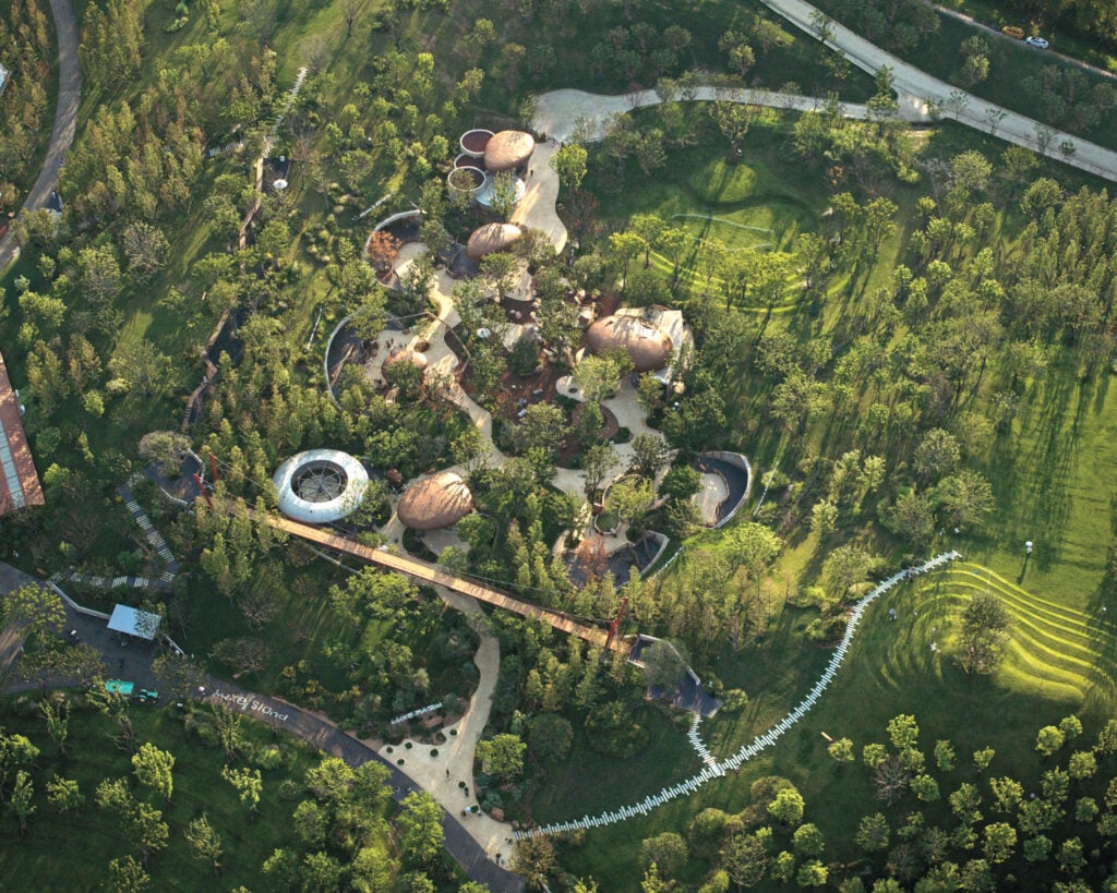 Aerial view of a lush, green park with winding pathways and several dome-shaped structures nestled among trees