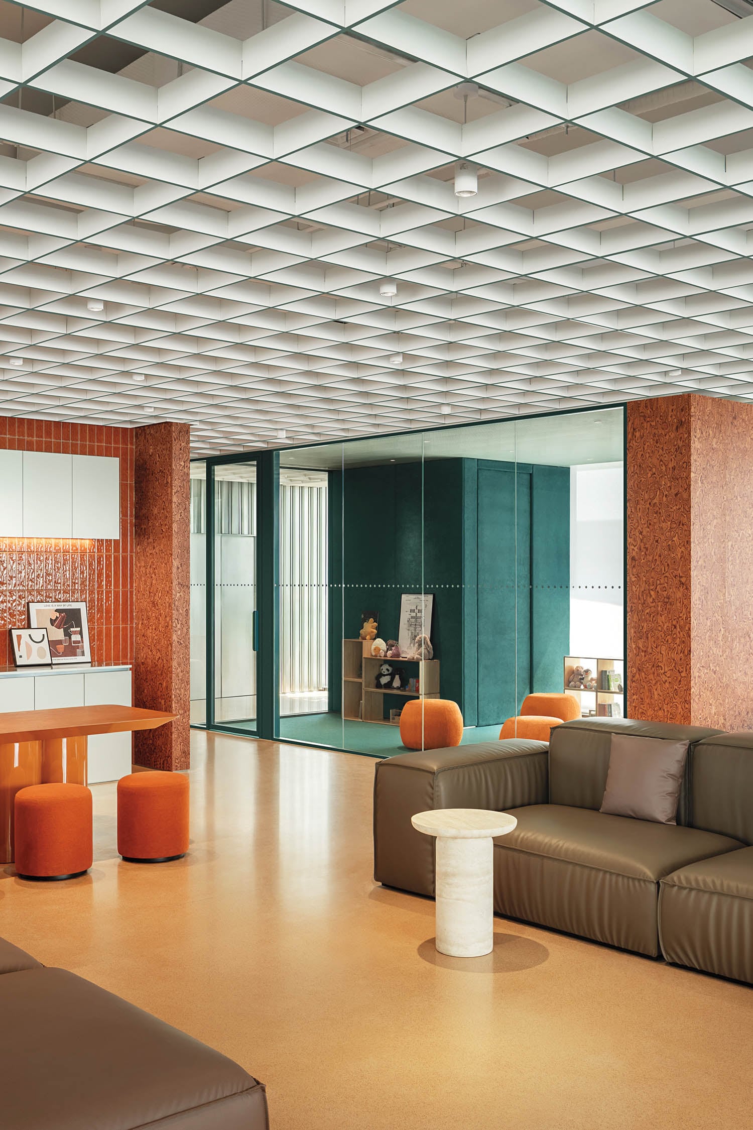 Modern lounge with brown leather sofas, orange stools, and a marble table