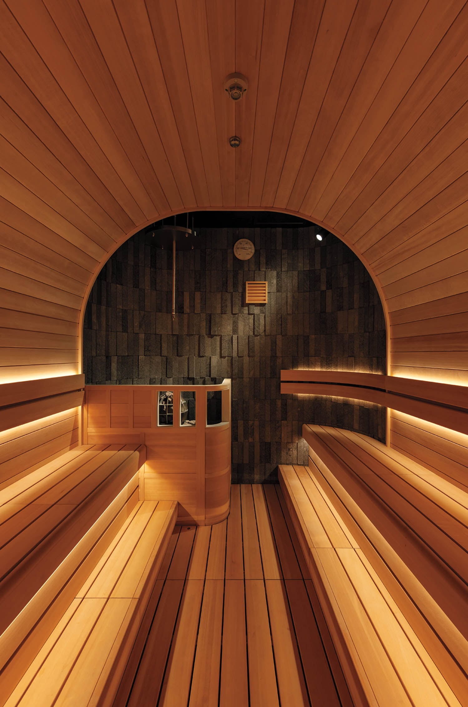 Warm, inviting sauna interior featuring curved wooden benches and walls, soft ambient lighting, and a serene atmosphere