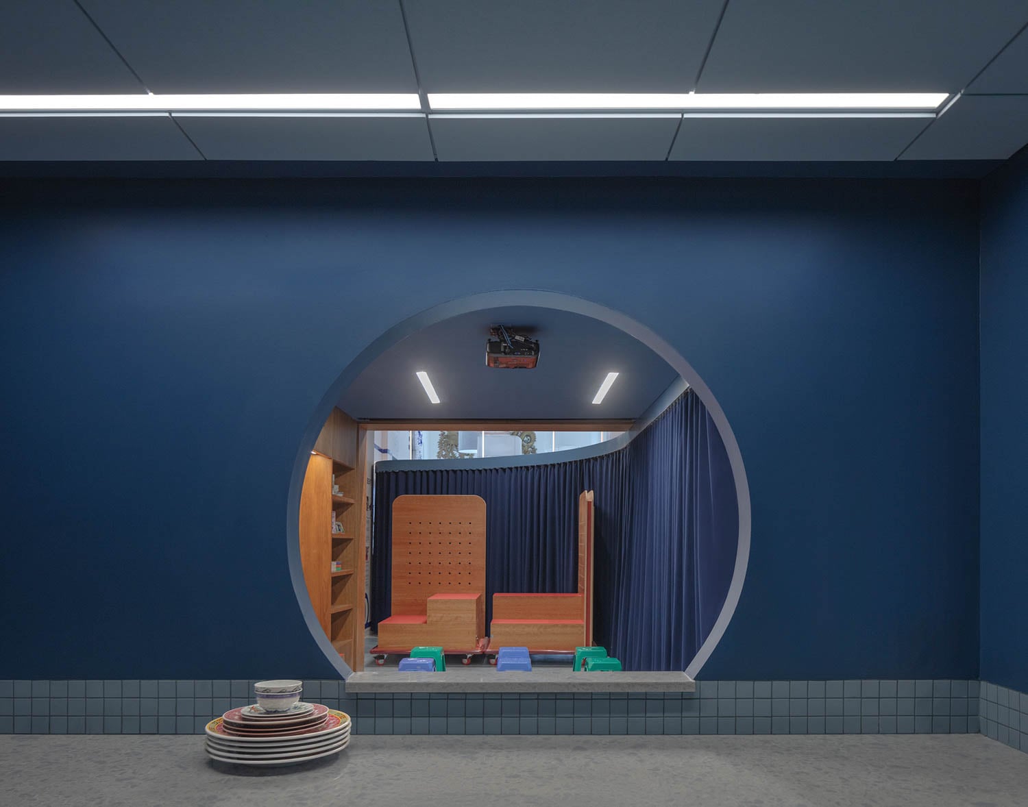 A modern room with a circular entrance framed by deep blue walls and curtains