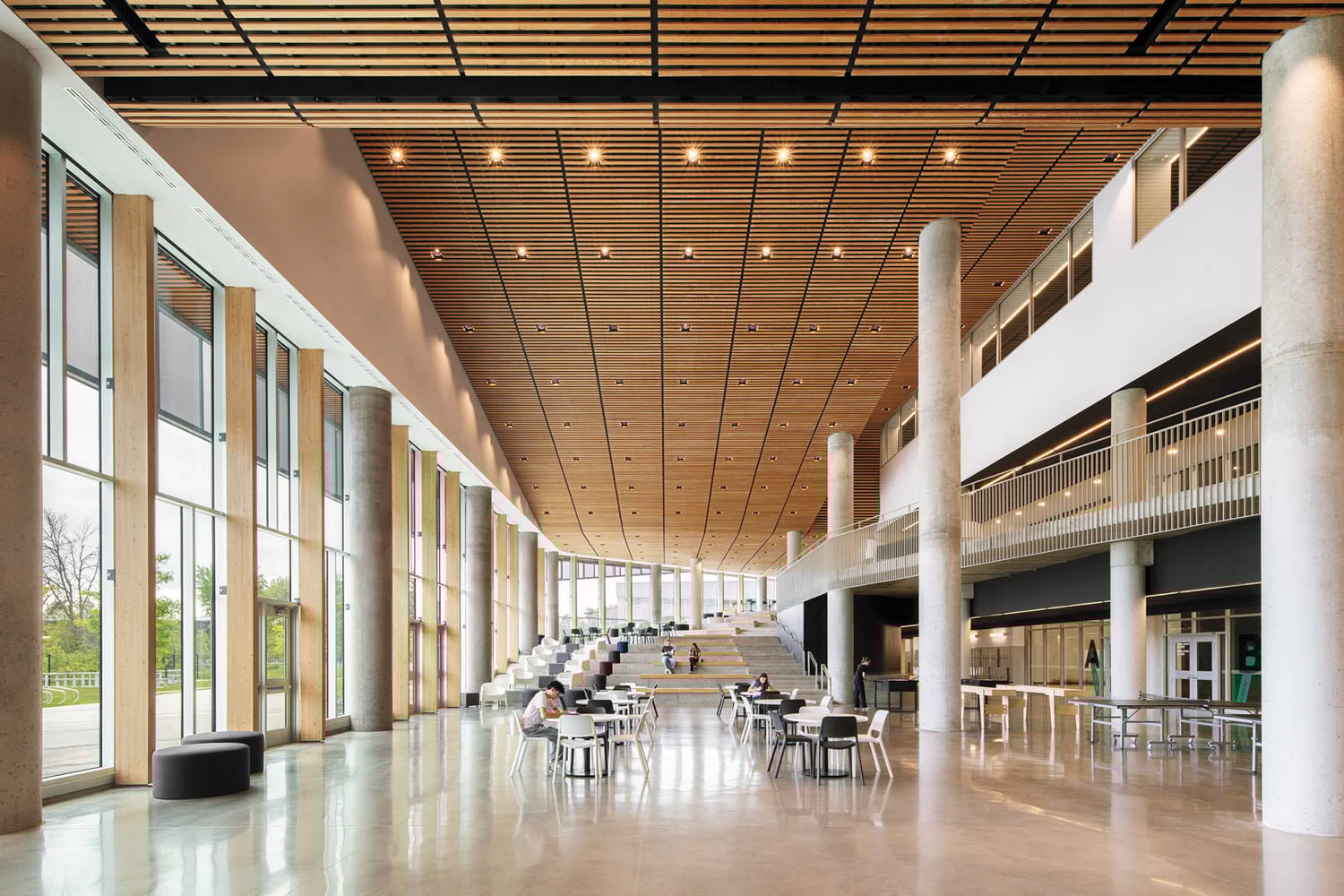 Spacious, modern atrium with tall windows, wooden ceiling, and concrete pillars