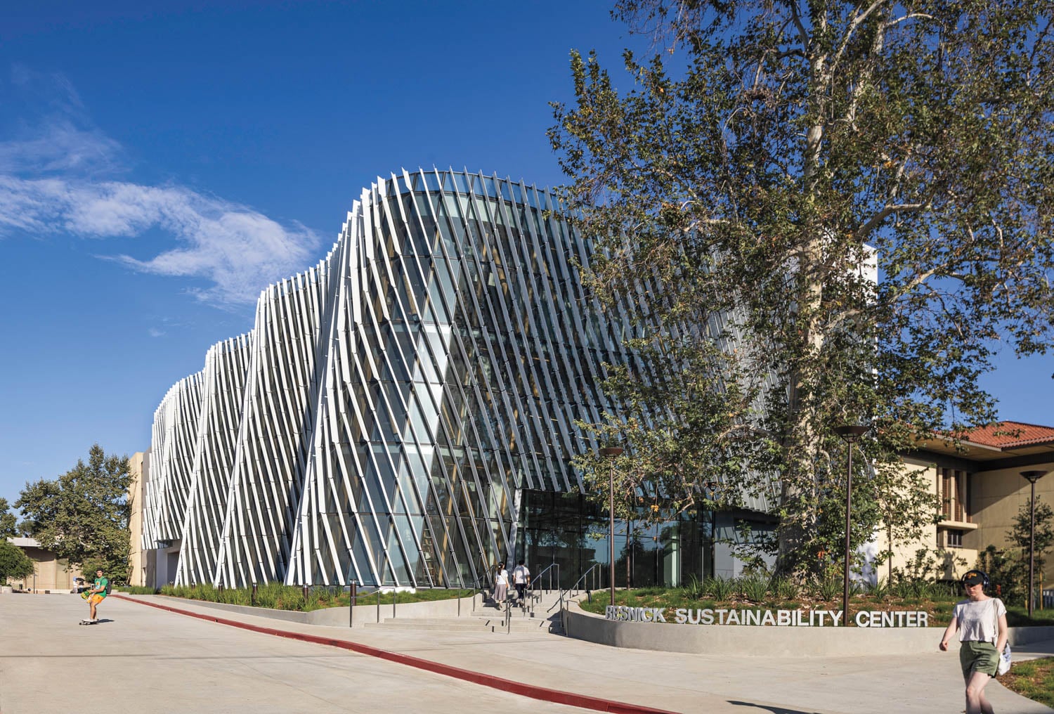 A modern building with a wavy, glass facade under a clear blue sky