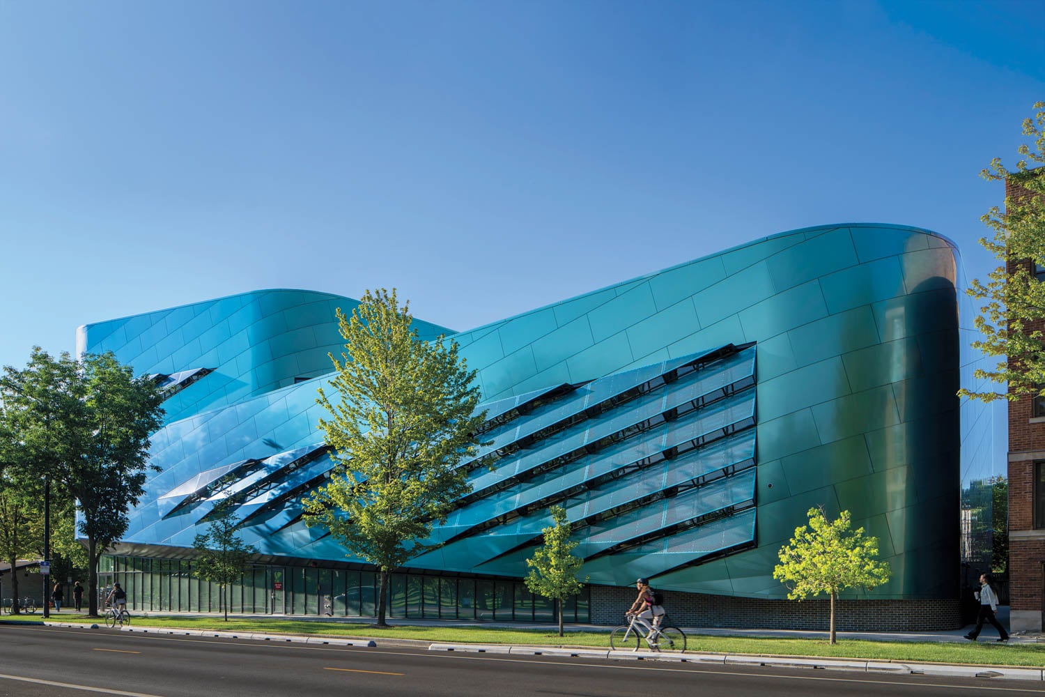 Futuristic teal building with curved design and diagonal windows, set against a clear blue sky