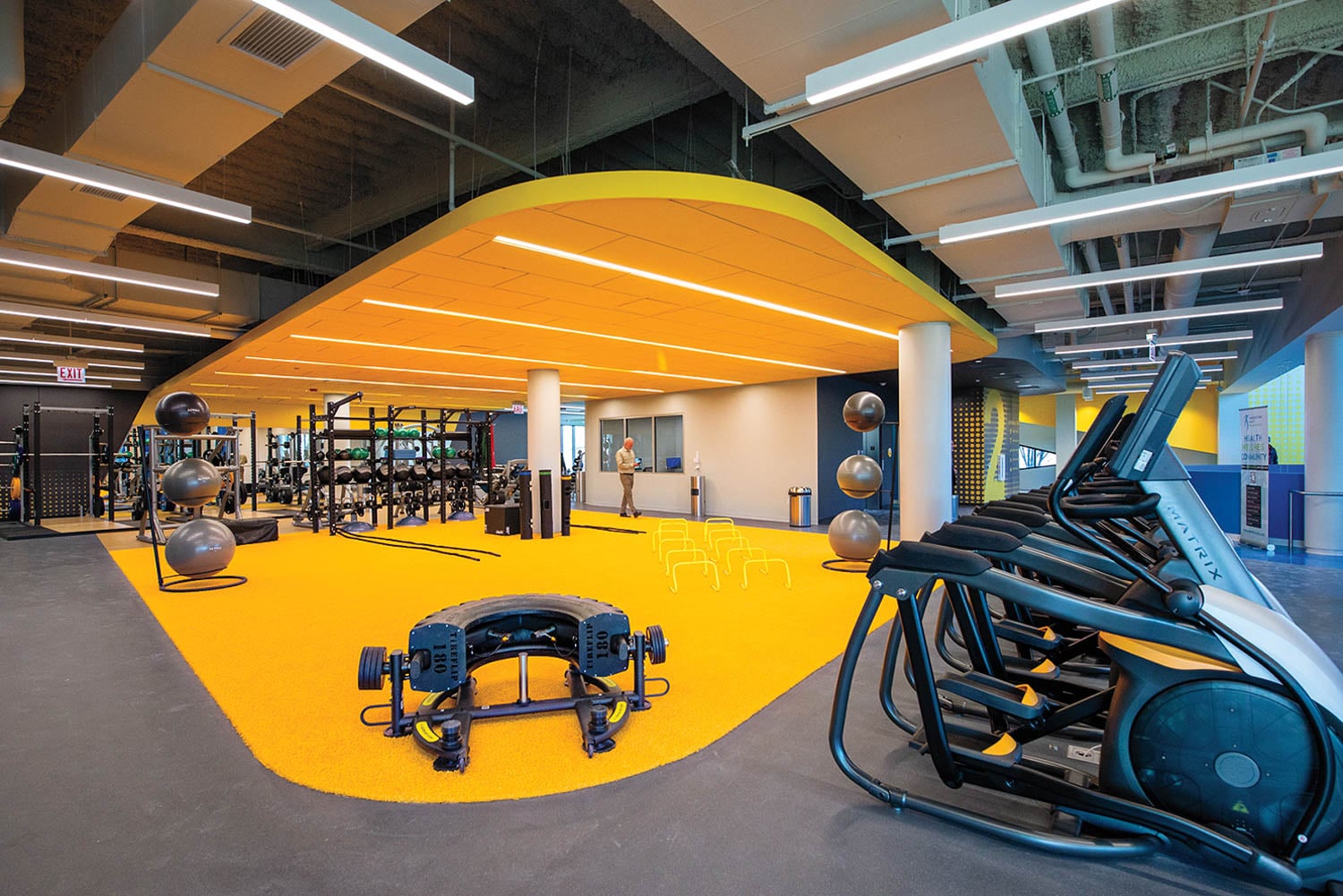 Modern gym with vibrant yellow flooring and ceiling.