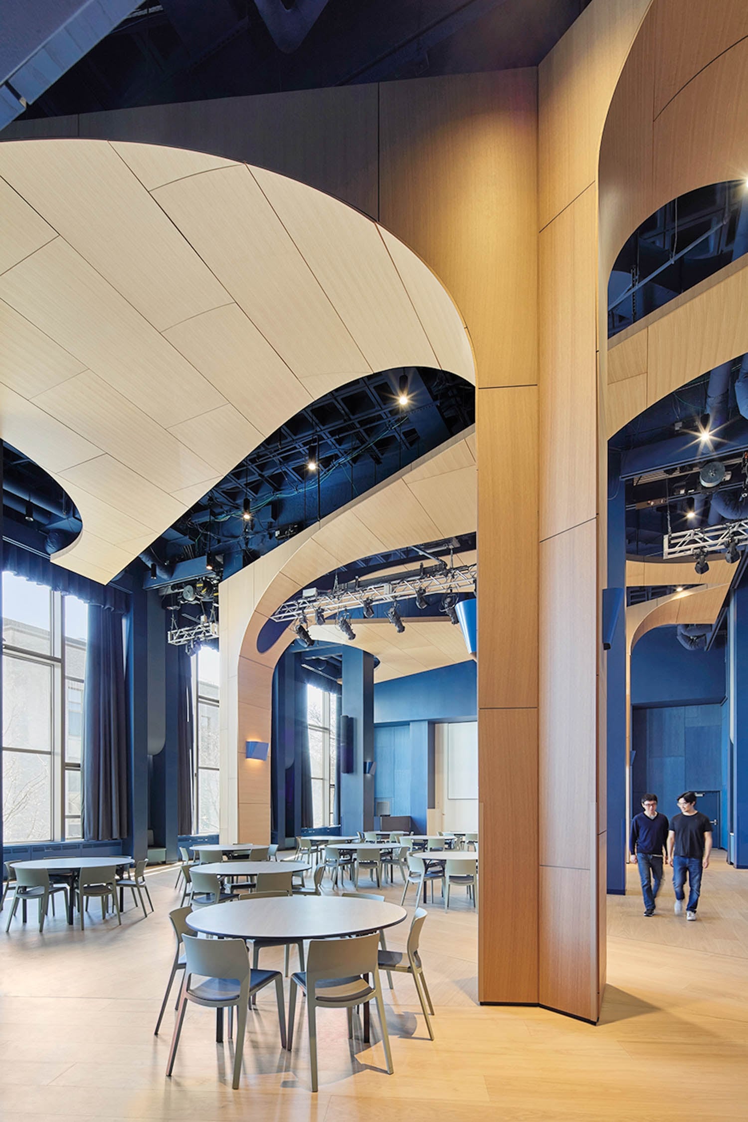 A modern interior with high wooden arches, large windows, and blue accents