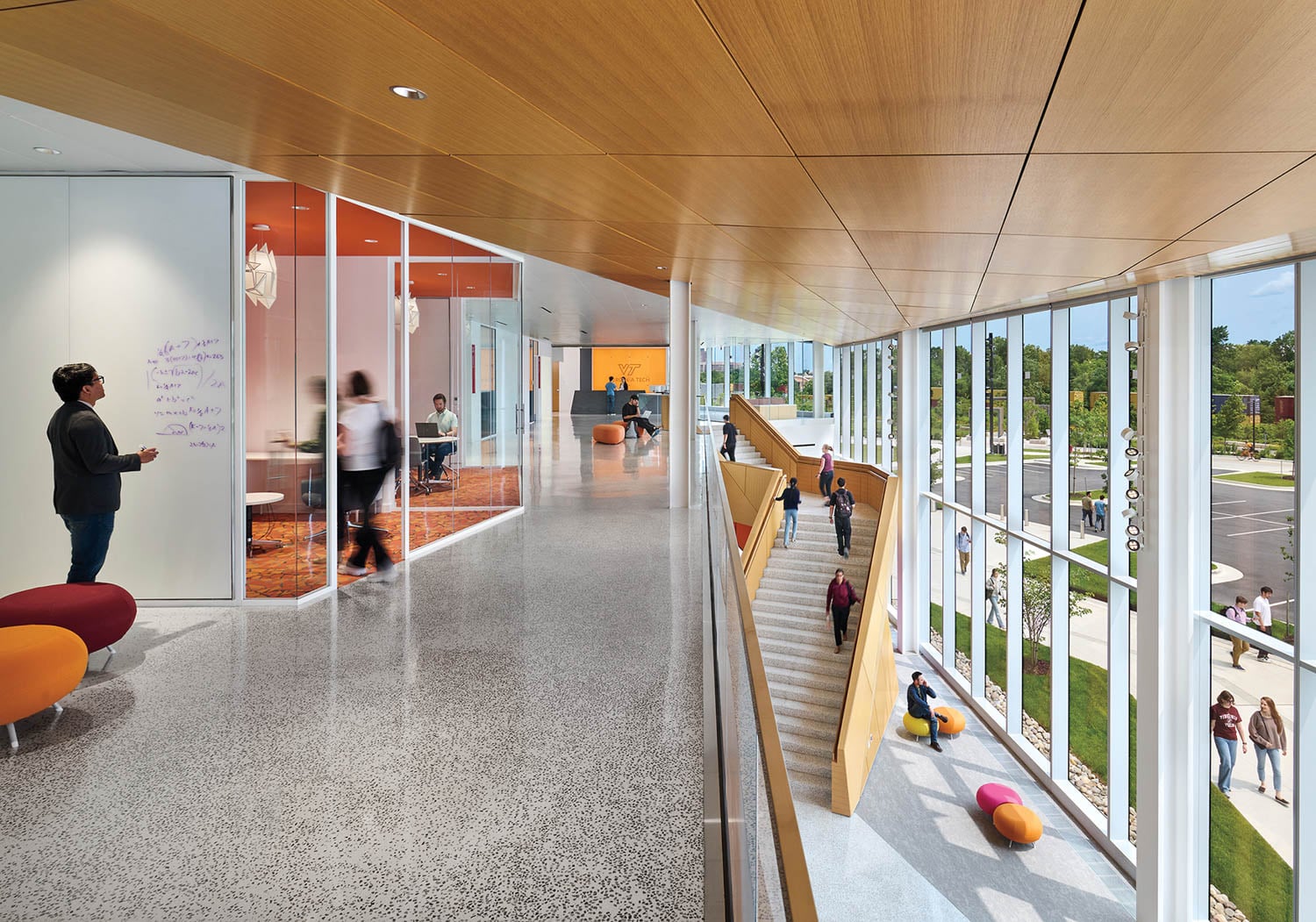 Modern school hallway with wooden ceiling, glass walls, and large windows