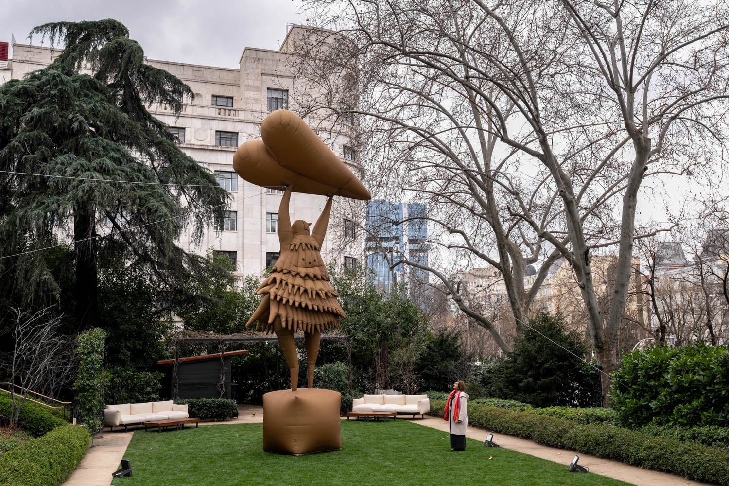 person standing in park with a tall bronze sculpture holding a heart