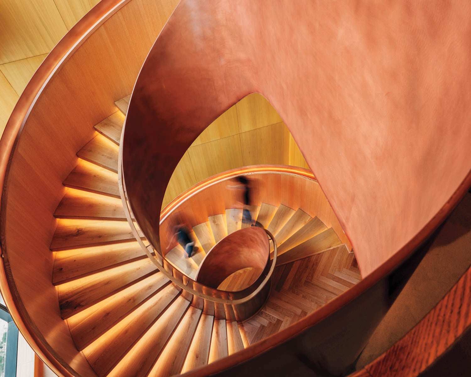 Aerial view of a spiral staircase with wooden steps and warm lighting