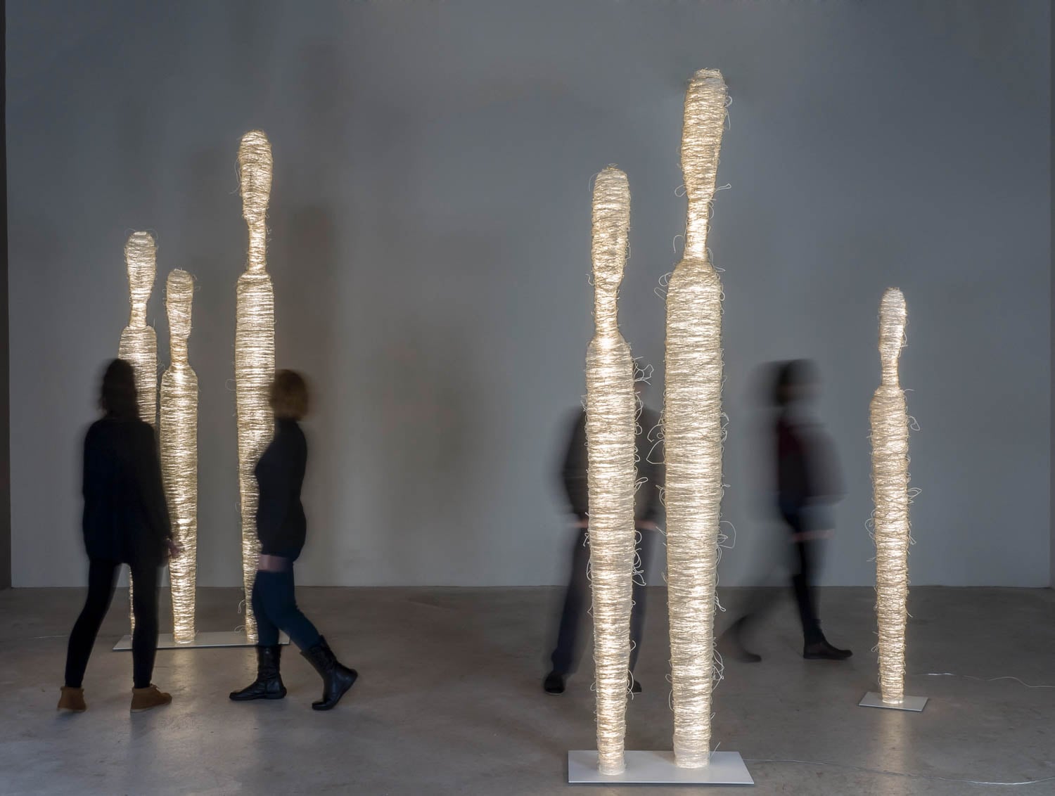 white sculptures with people walking between