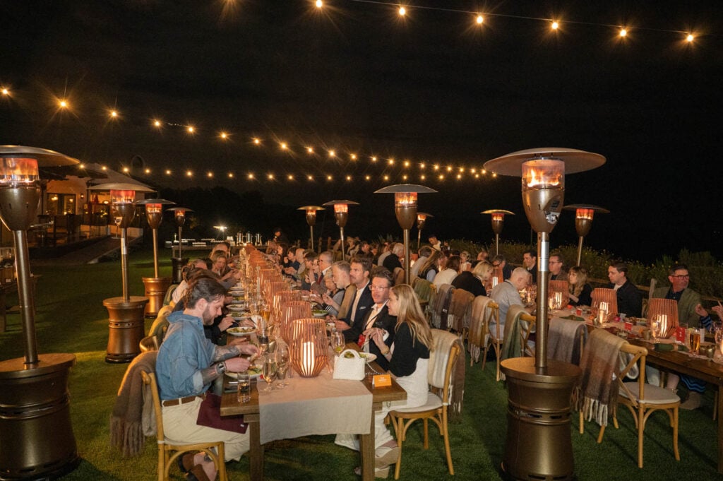 designers dining outdoors overlooking the ocean under twinkle lights
