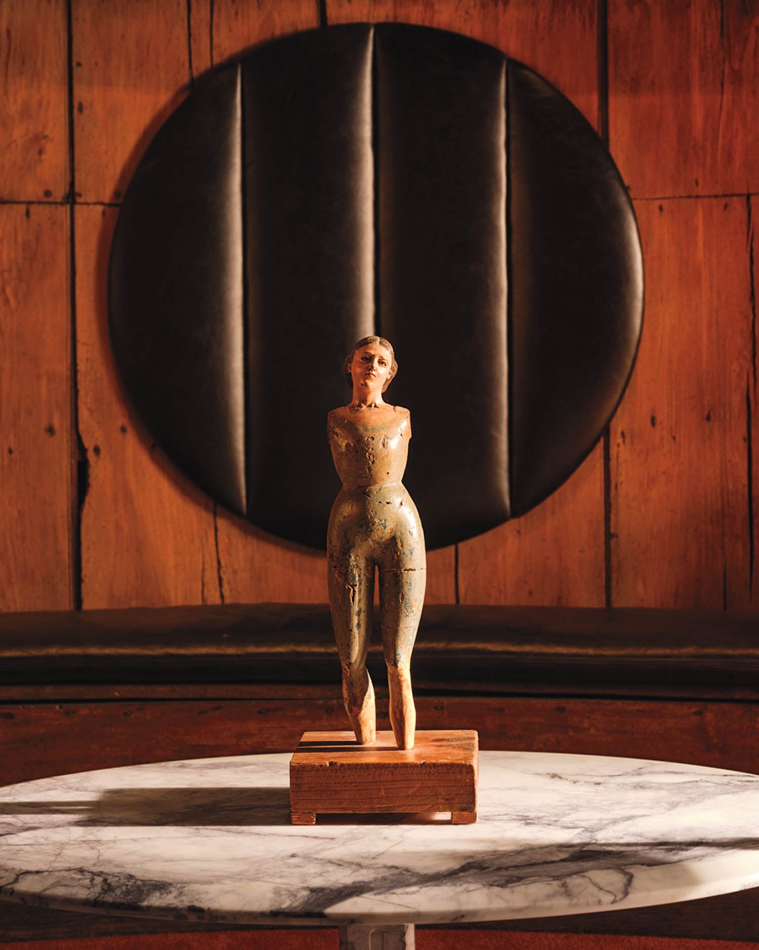 a sculpture of a person near a wood wall