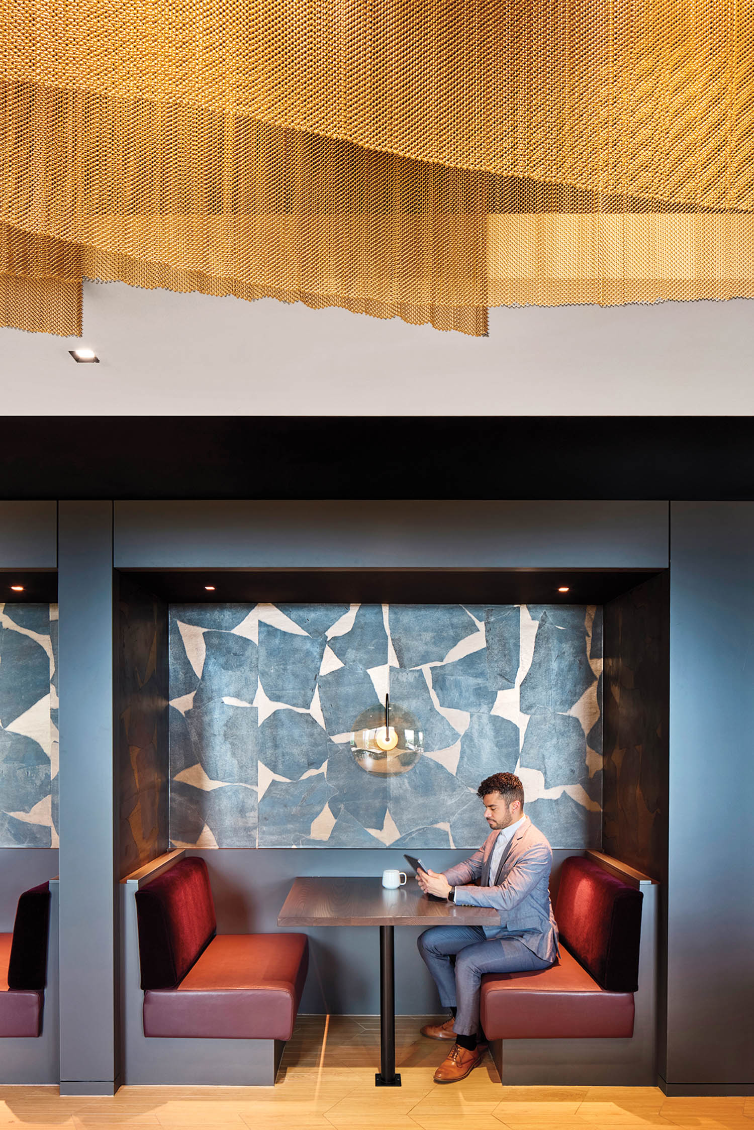 person sitting at booth with red chairs and blue backdrop