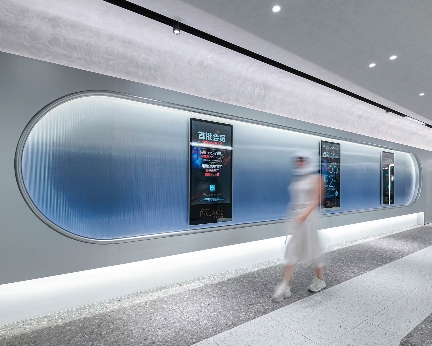 A modern hallway with smooth, curved walls and backlit blue panels