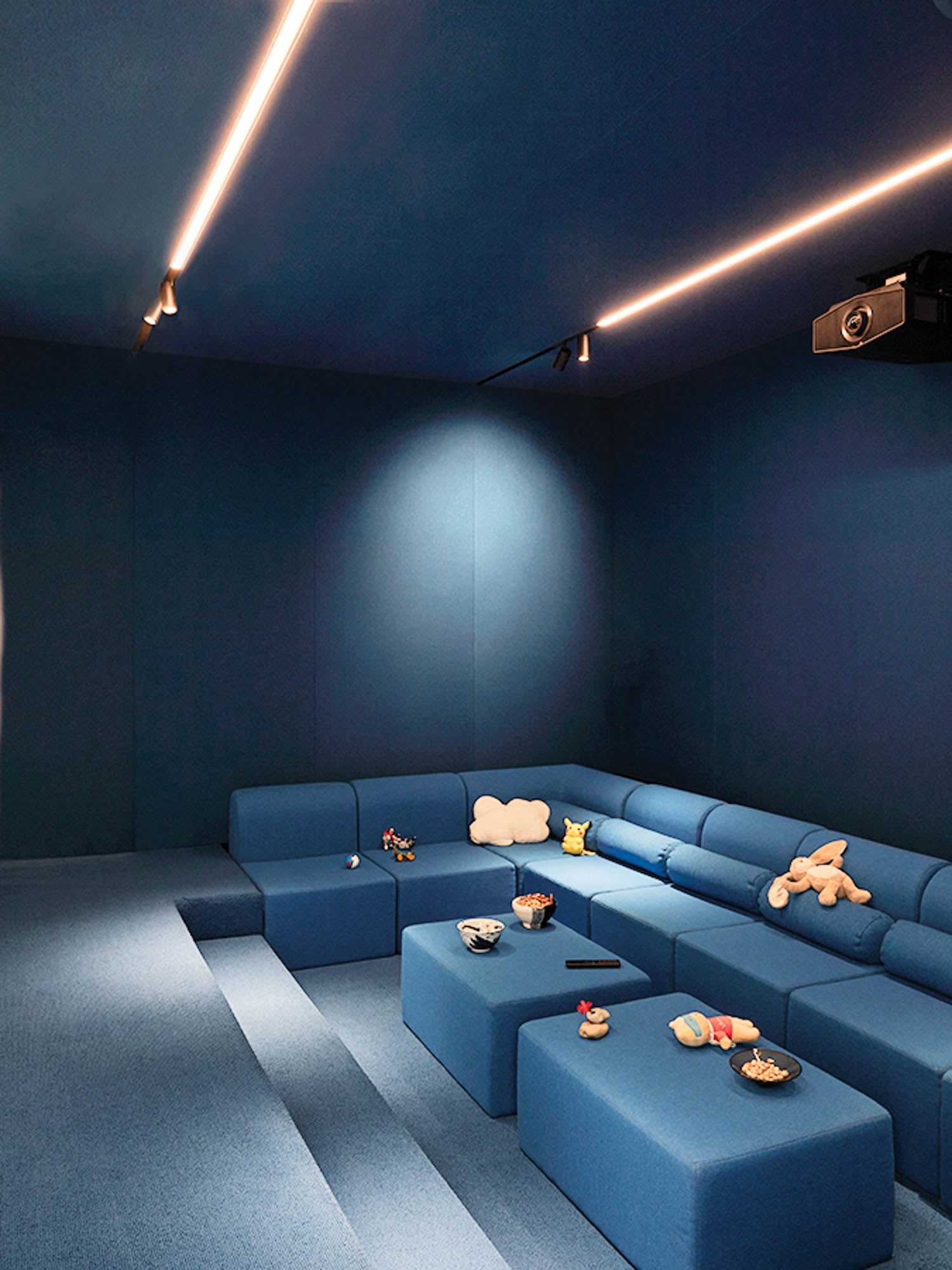 Modern blue home theater with a cozy, sectional sofa and dim lighting.
