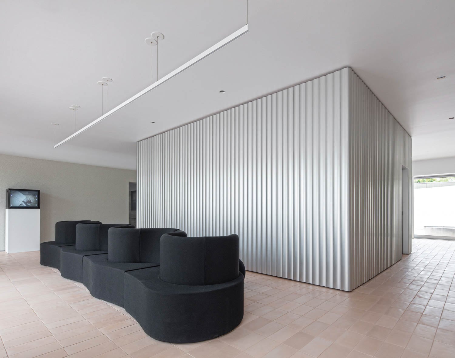 Modern minimalist interior with black modular seating and corrugated silver partition