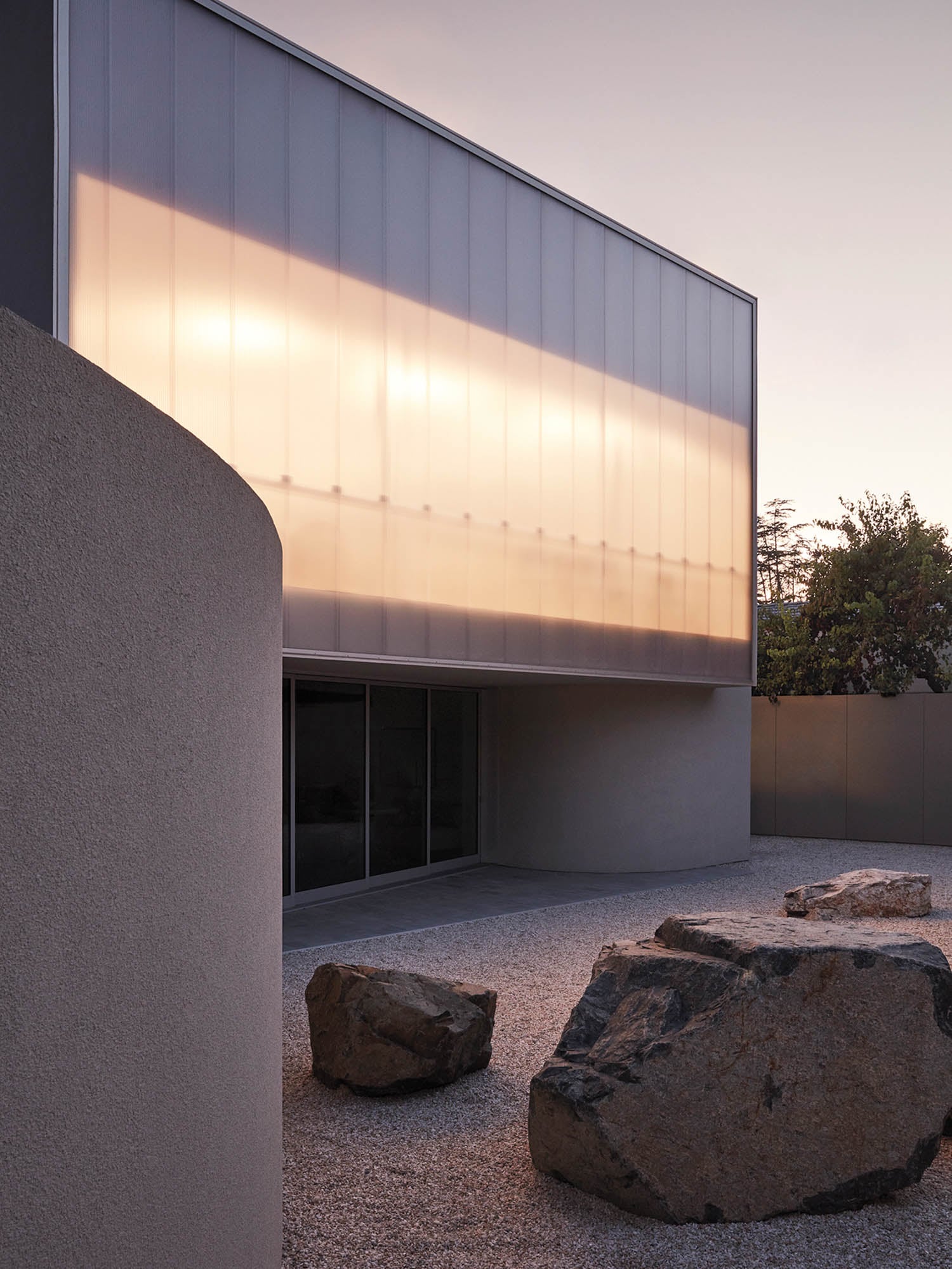 Modern architecture with a translucent facade glowing in sunset hues