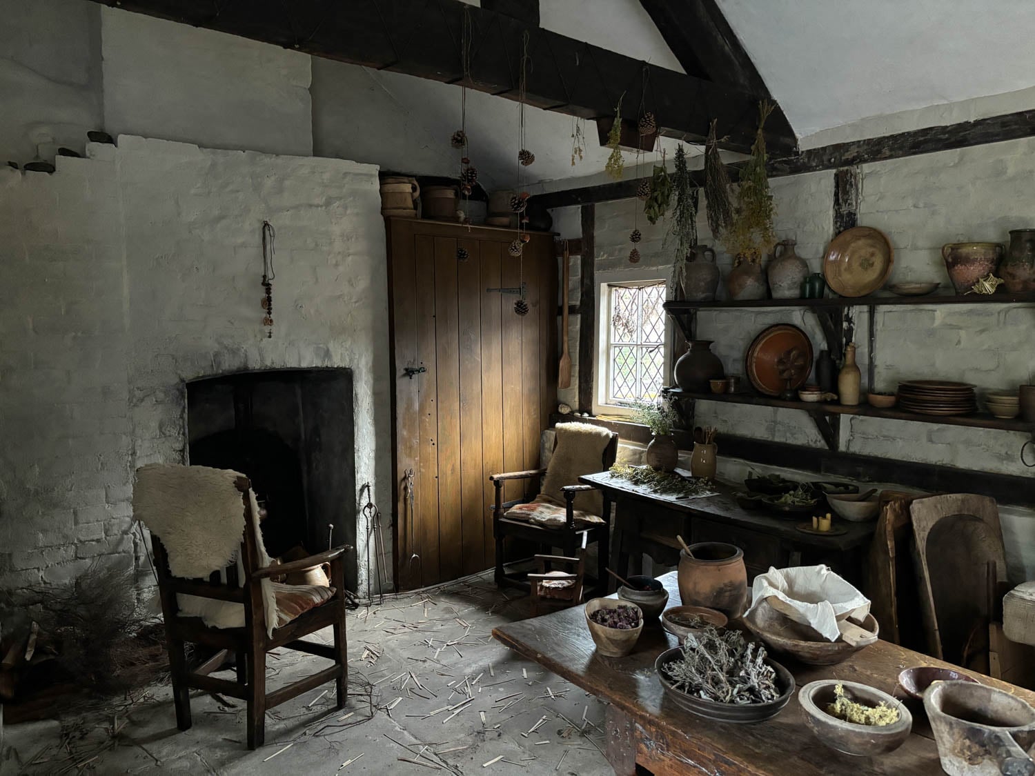 A rustic medieval kitchen with wooden beams, a fireplace, and stone walls