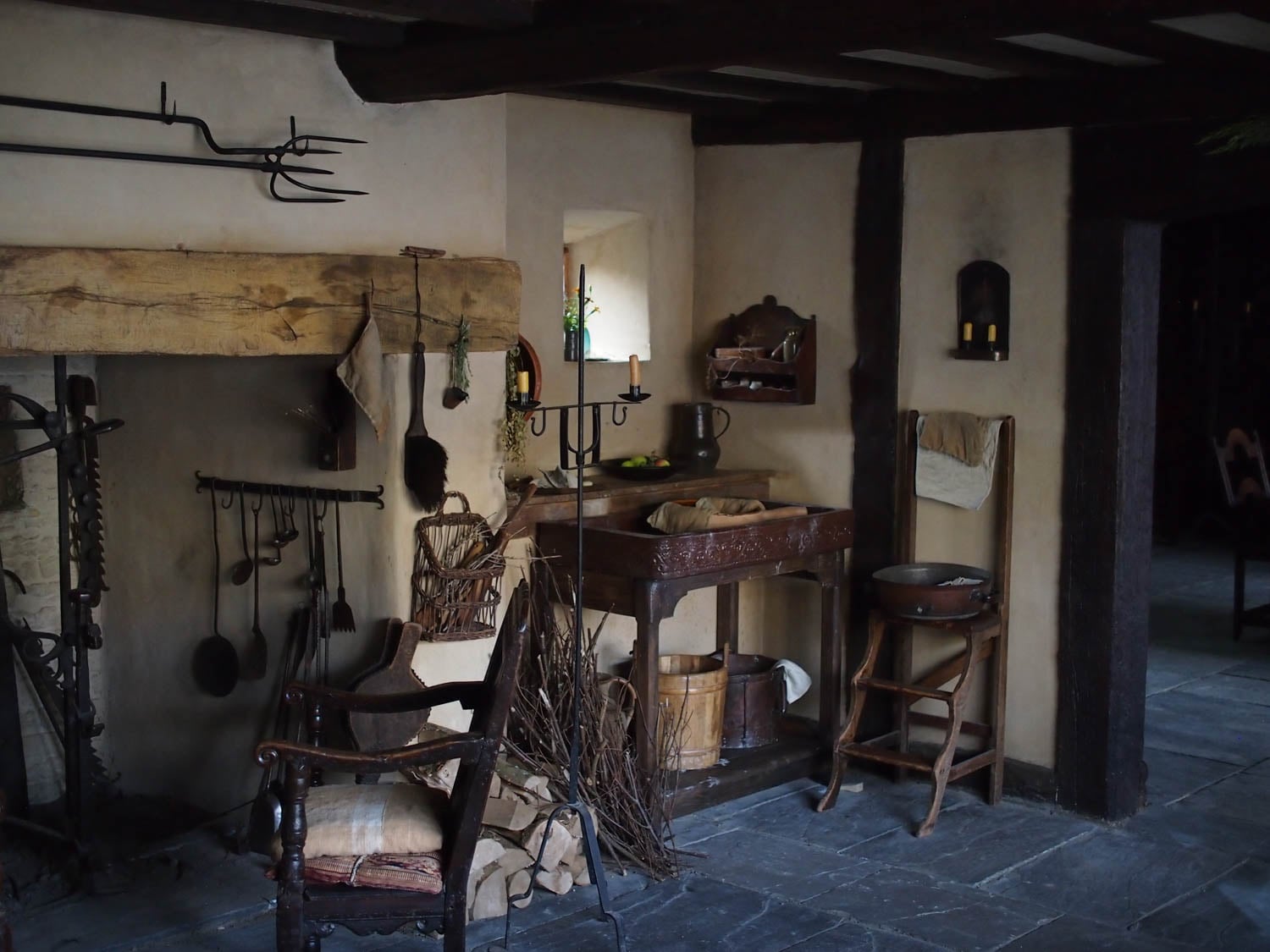 Dimly lit rustic kitchen with a large wooden beam above the fireplace