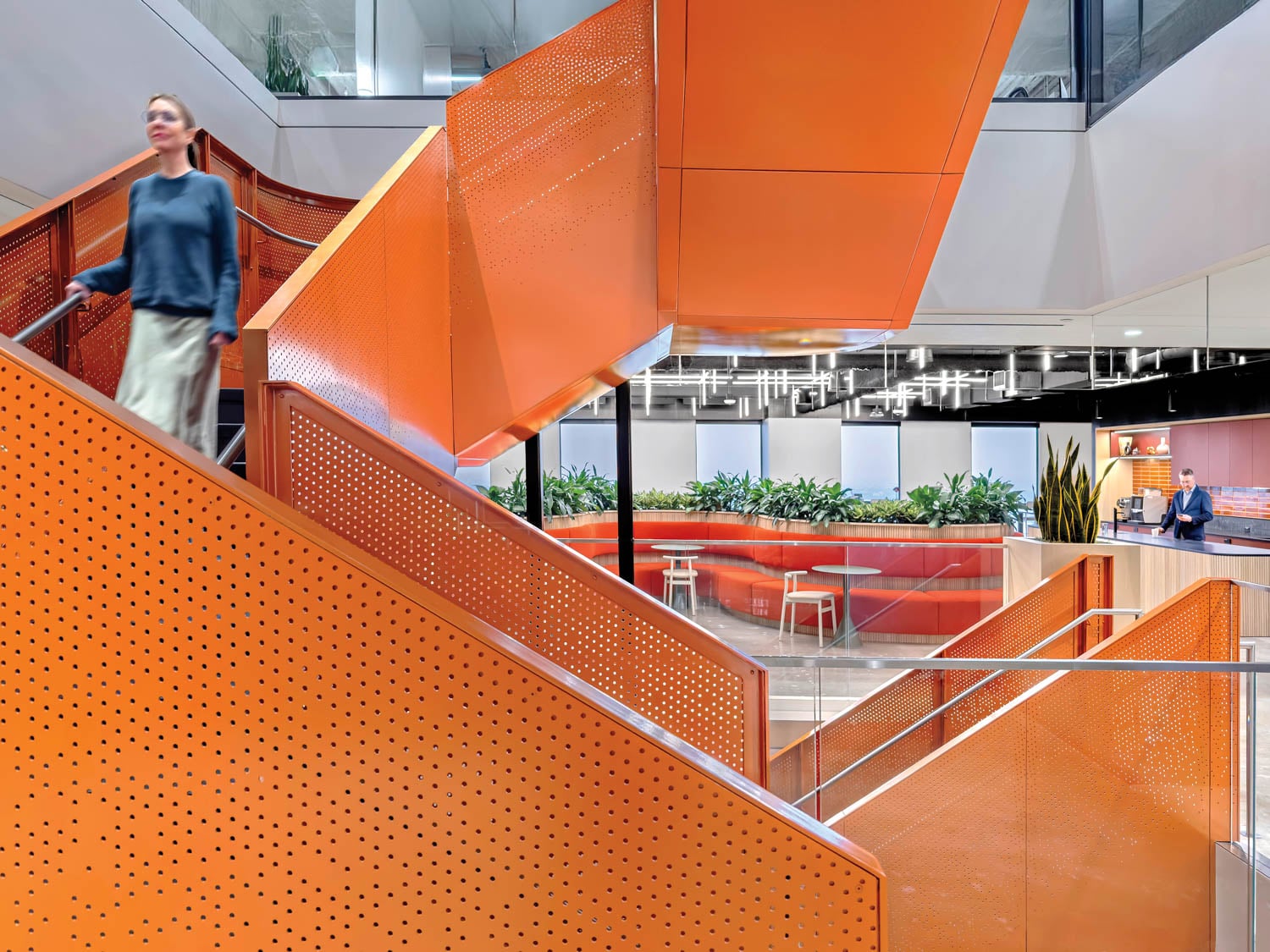 Modern office interior with a vibrant orange staircase and perforated panels