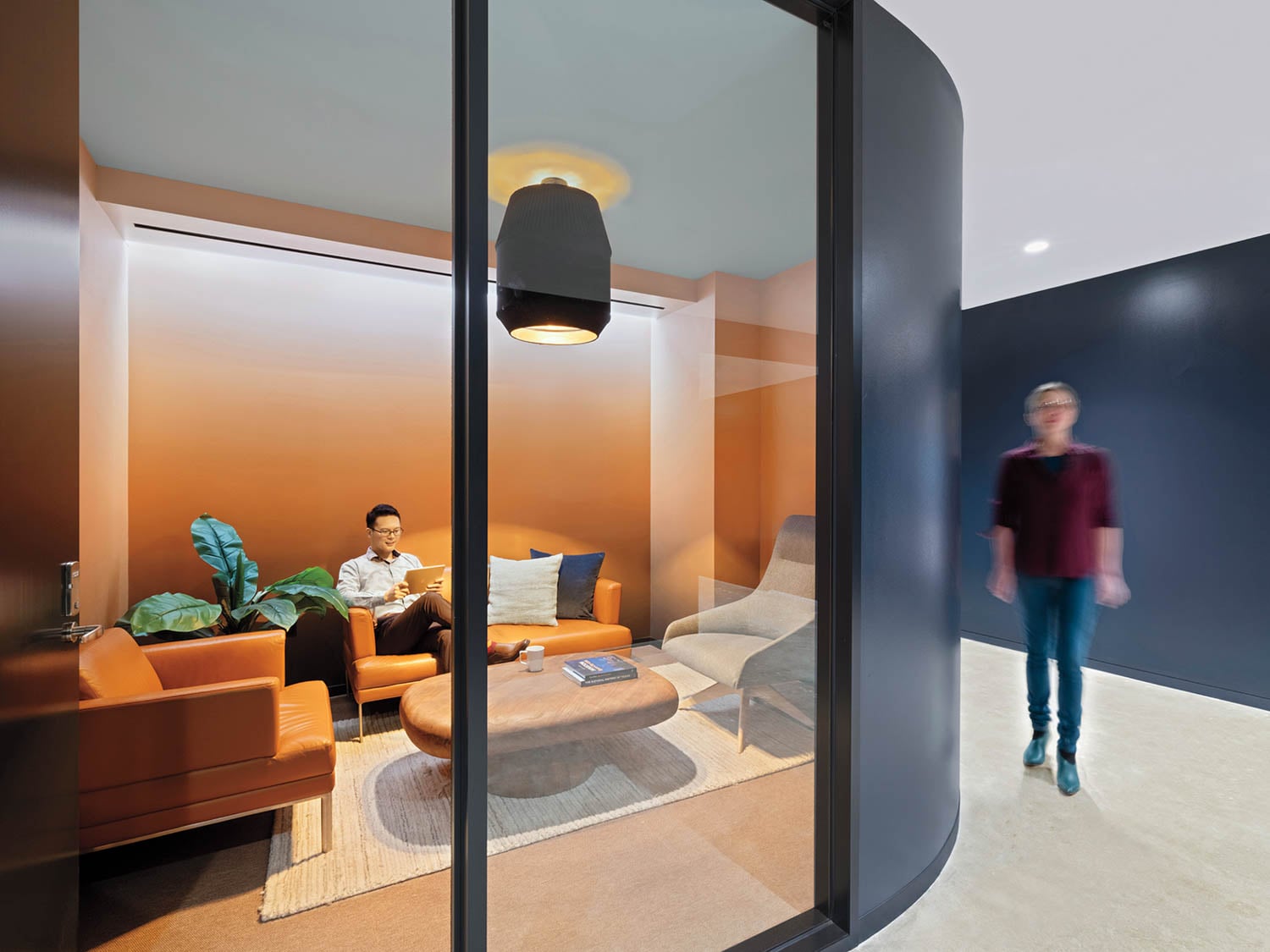 Modern office lounge with orange walls and brown leather sofas