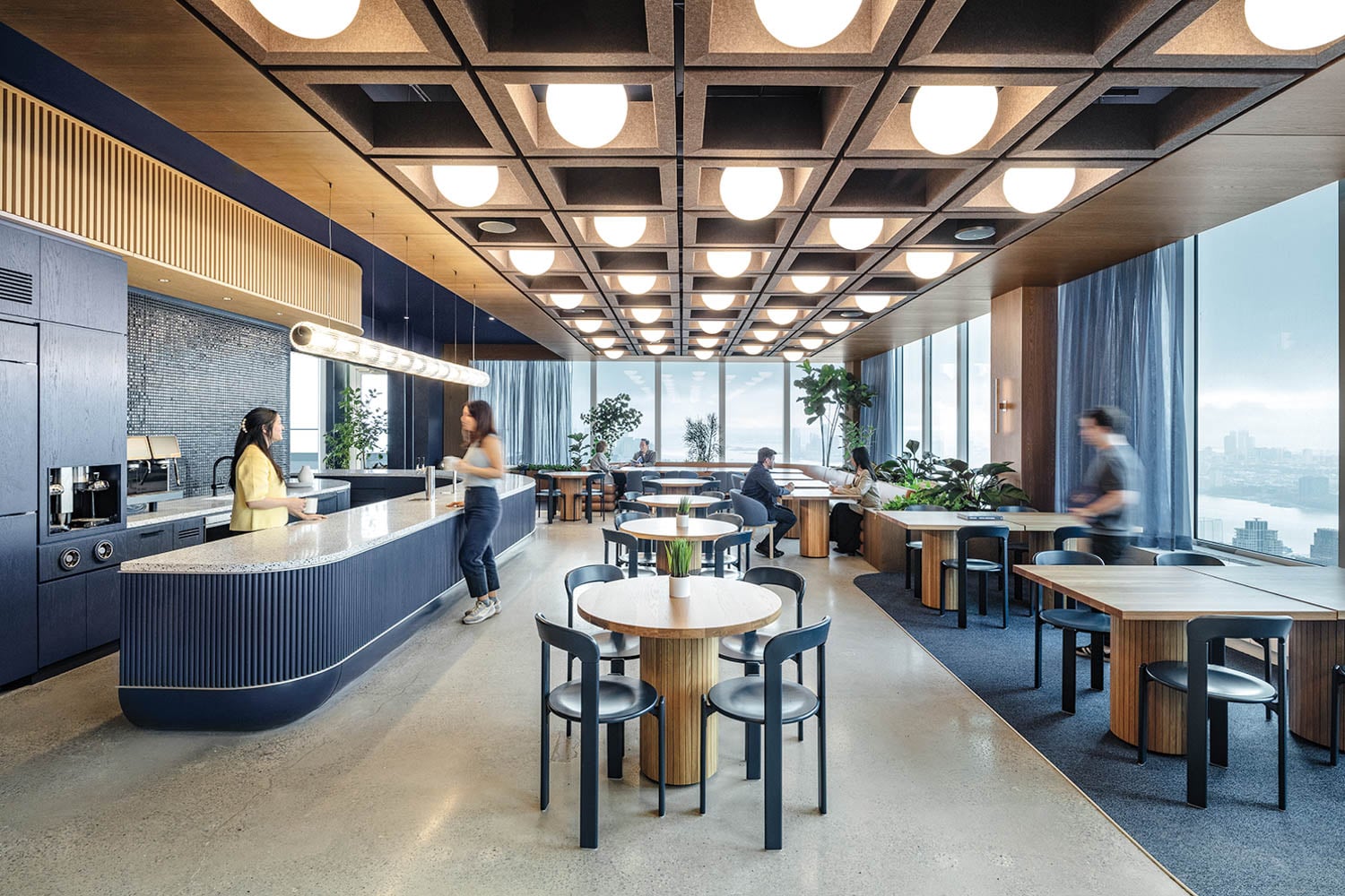 Modern office lounge with round tables, black chairs, and ceiling lights