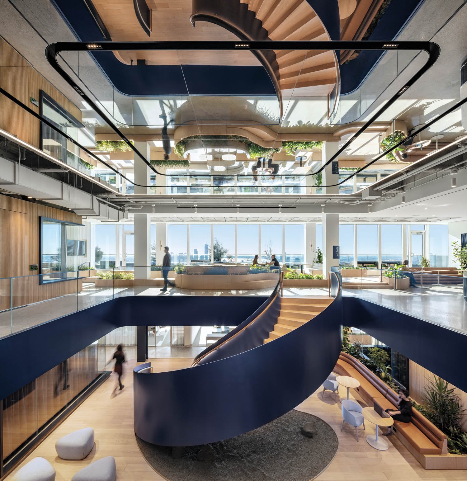 Modern office atrium with a spiral staircase, glass ceiling, and panoramic city view