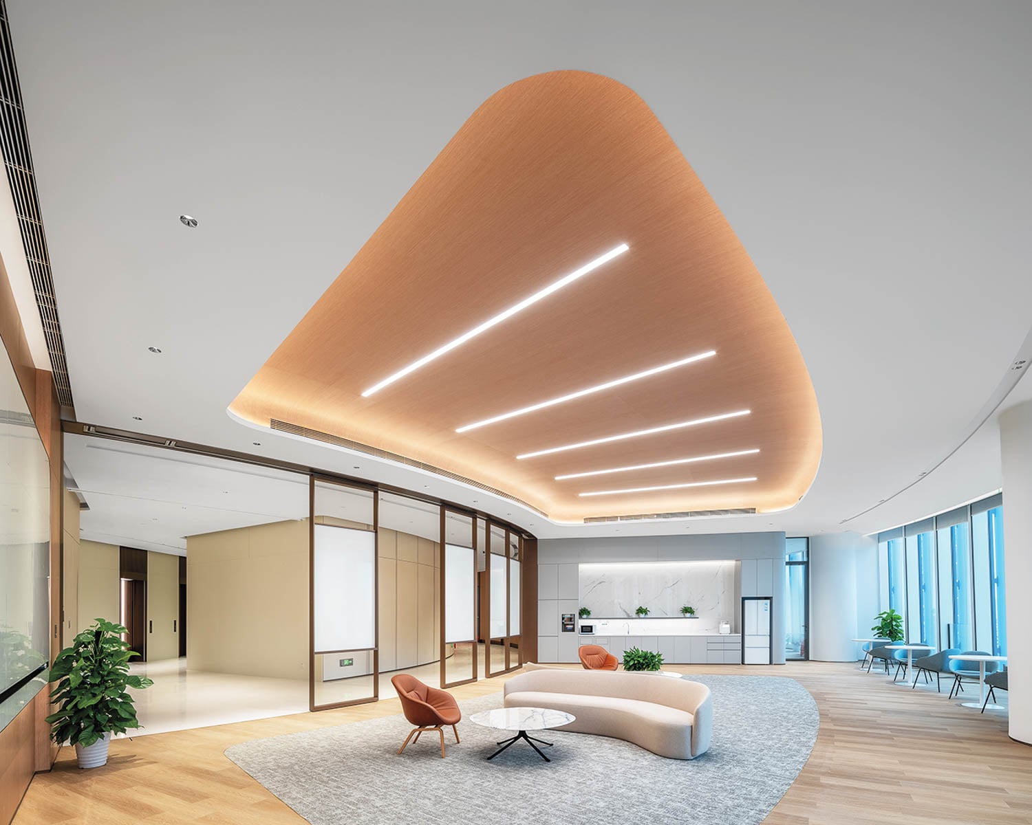 Modern office space with a curved ceiling featuring linear lights, sleek furniture, a cozy sofa, and large windows