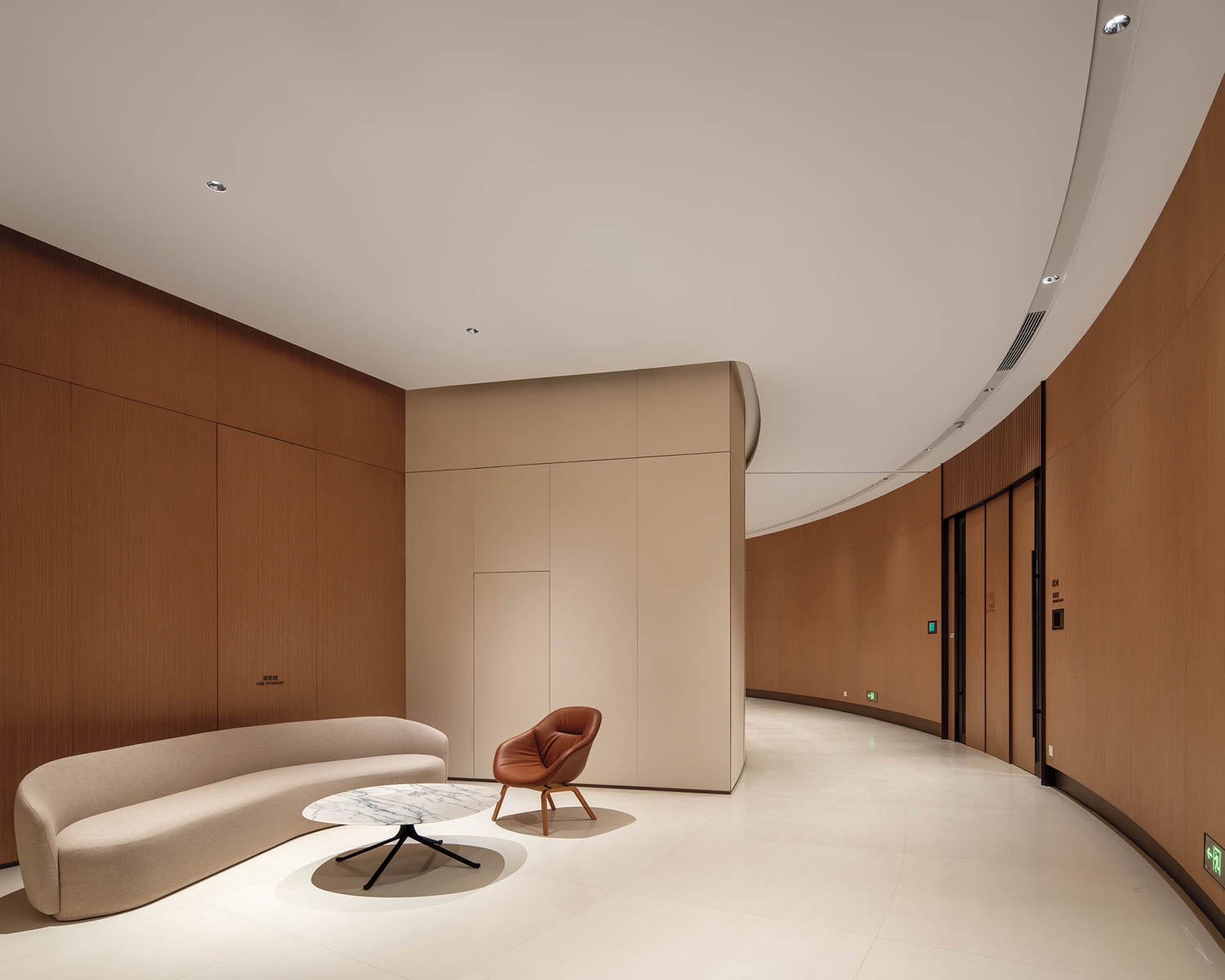 Modern minimalist interior with curved wooden walls, a beige sofa, brown chair, and marble coffee table