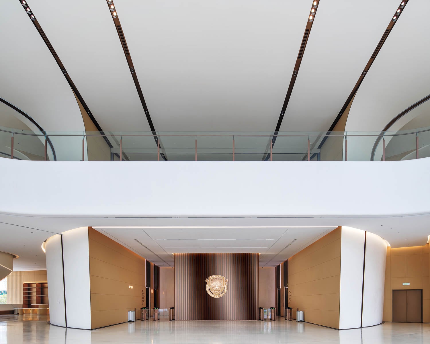 Spacious modern lobby with high ceilings, sleek lines, and a large emblem on the back wall