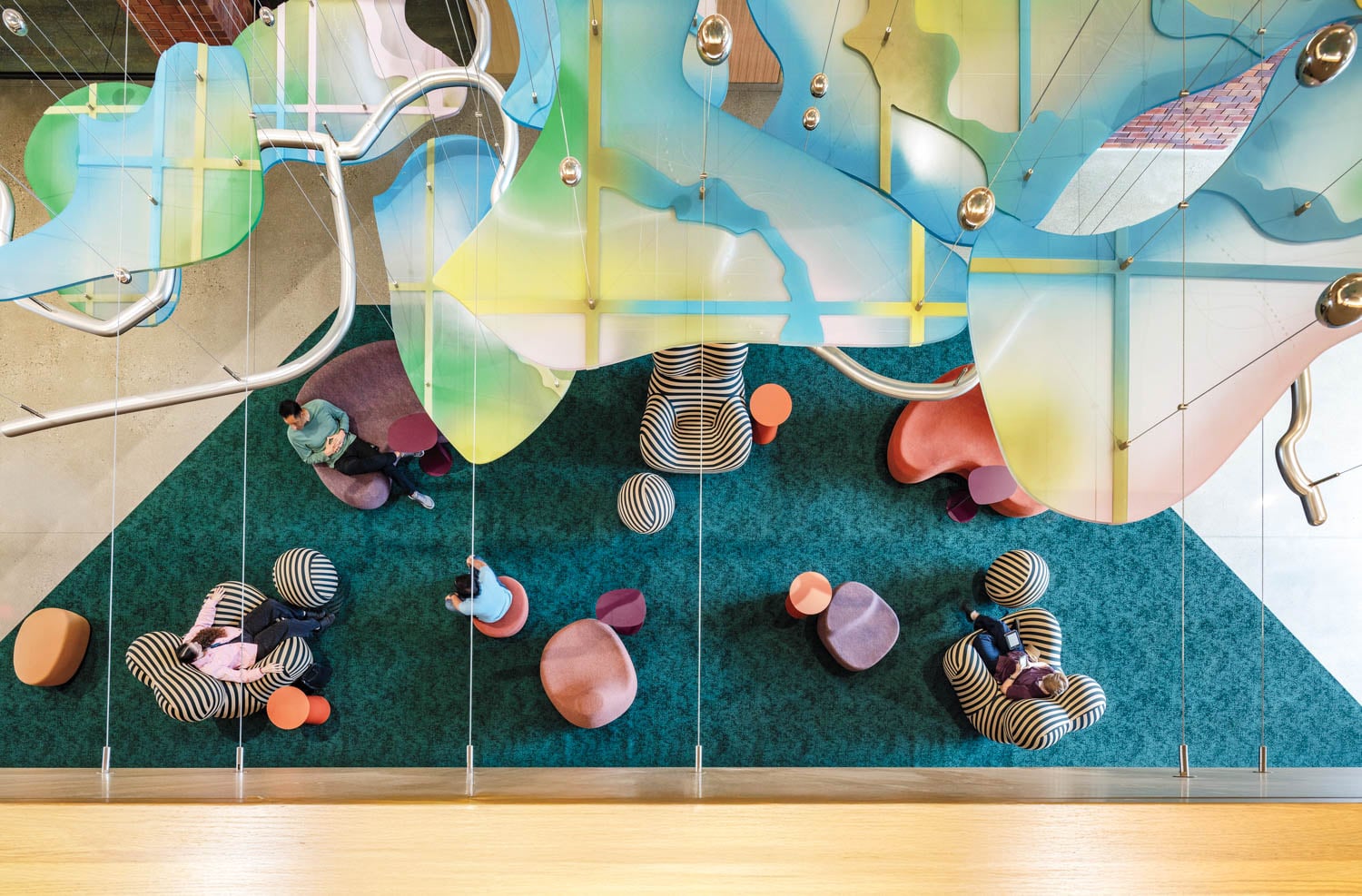Overhead view of a vibrant lounge with colorful, abstract ceiling art above a teal carpet
