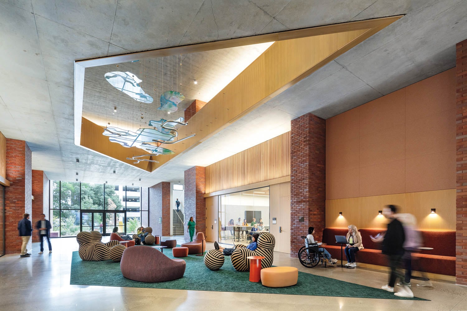 Modern lobby with brick walls, geometric seating, and colorful ceiling art