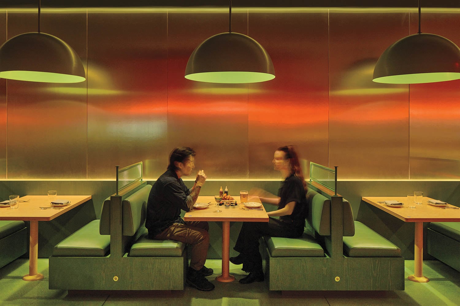 two people sitting at green booths