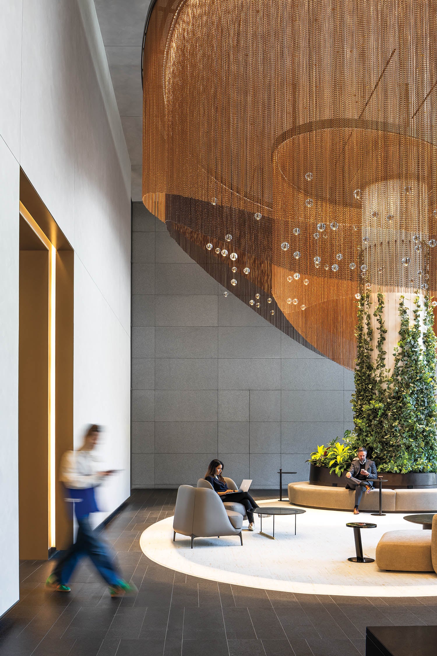 person walking into lounge area with curved chandelier
