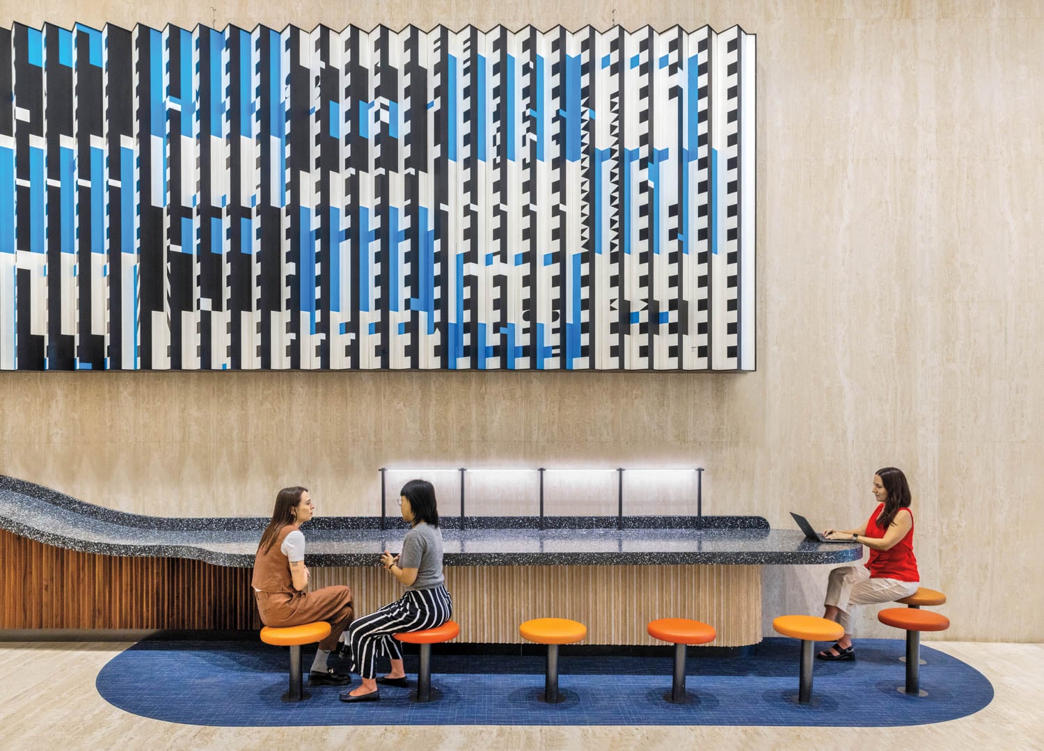people sitting at a long coffee bar under artwork