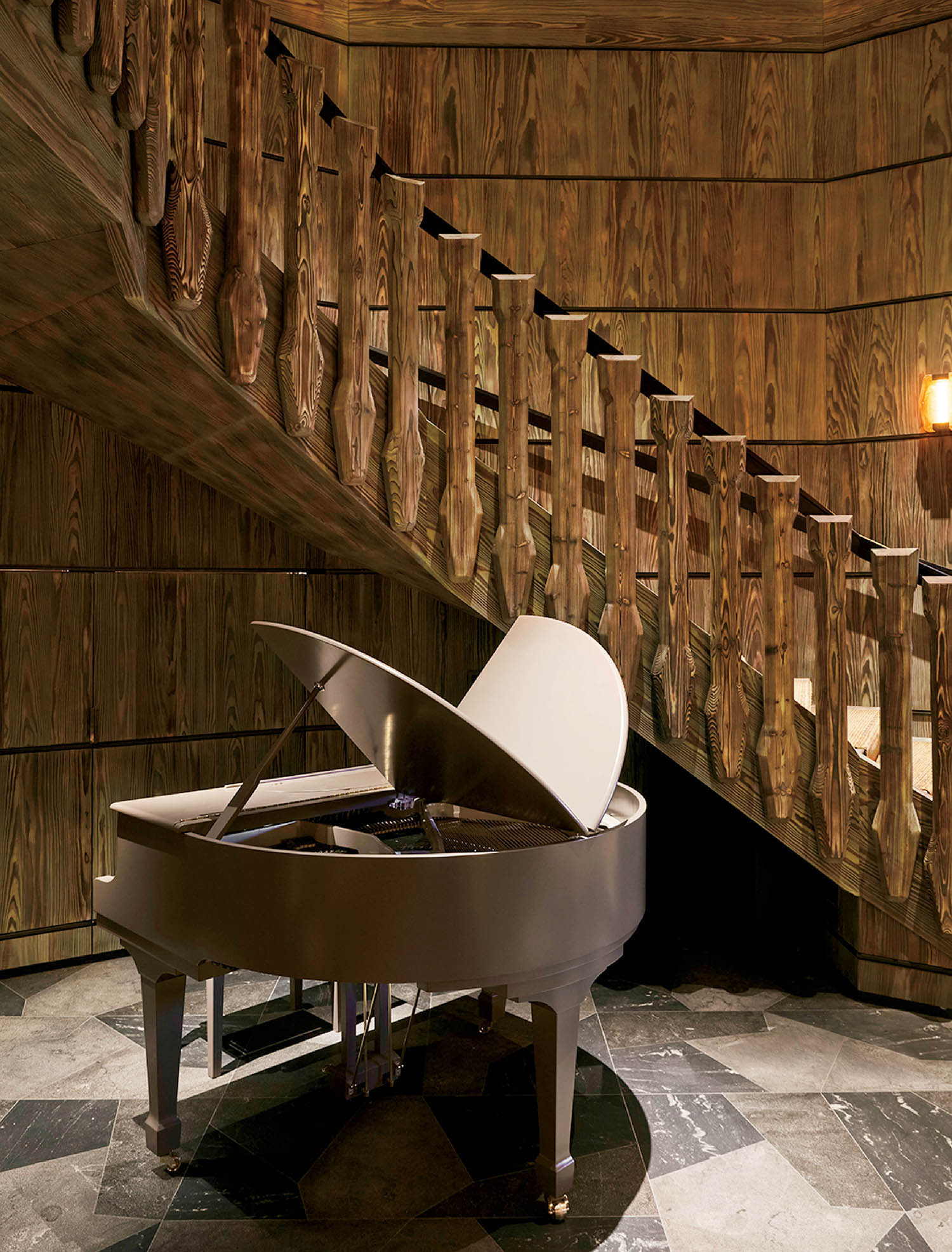 A grand piano in a room with a staircase.
