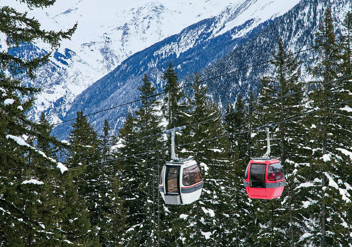 A ski lift going up a snowy mountain.