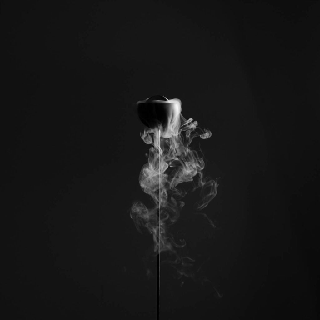 A single rose with smoke rising from it against a dark background.