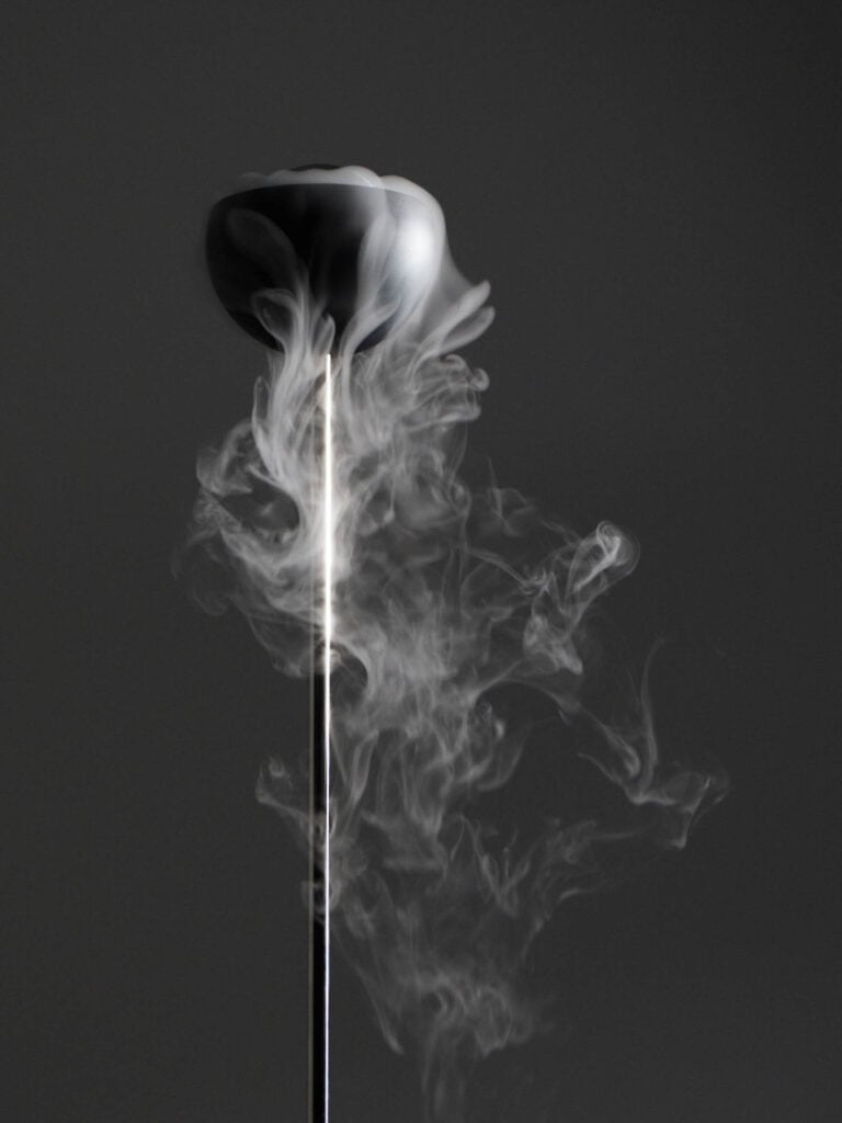 A black ladle emits swirling steam against a dark, plain background.