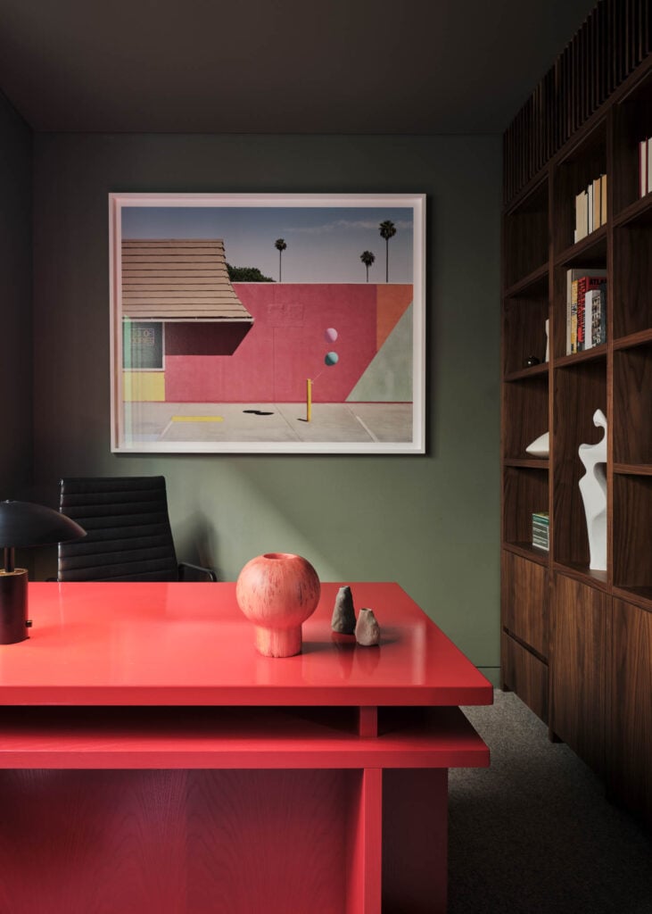red table with art on green wall