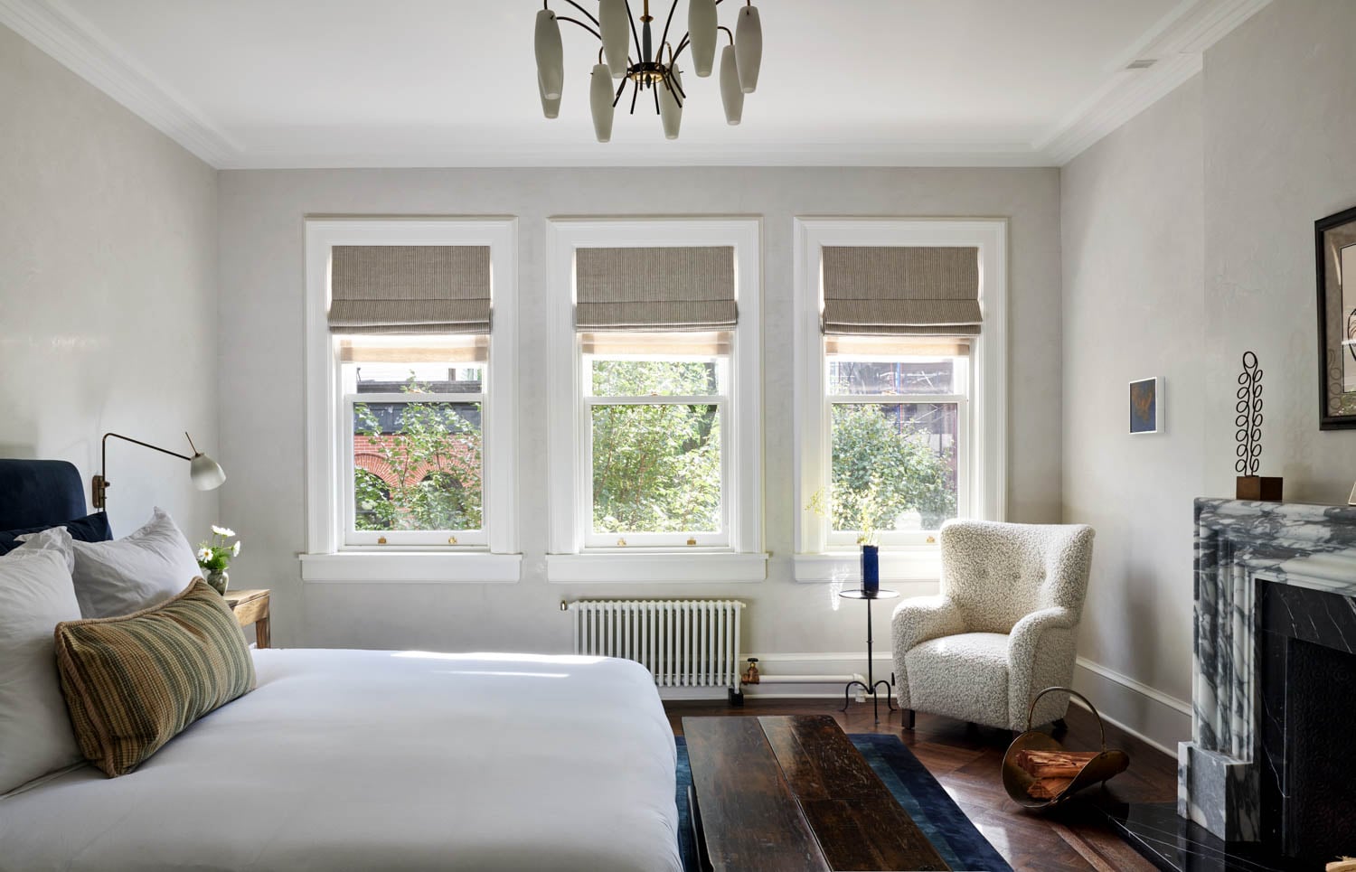 bedroom with white bed and chair and three windows