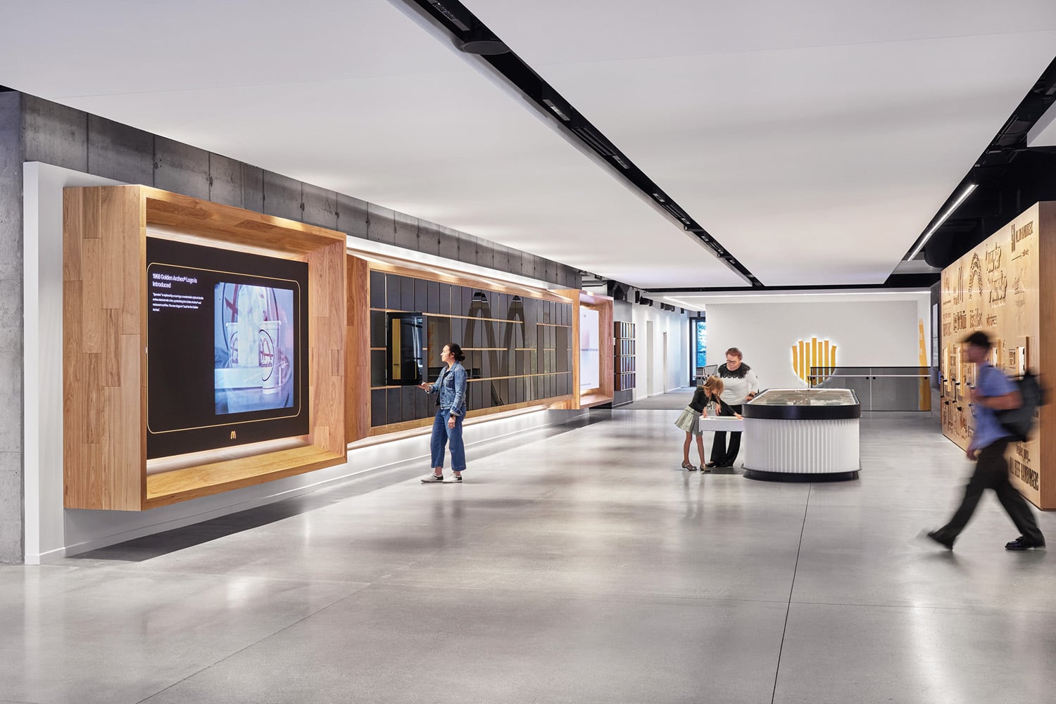 hickory millwork frames a grid of dark‑glass display cabinets flanked by video screens.