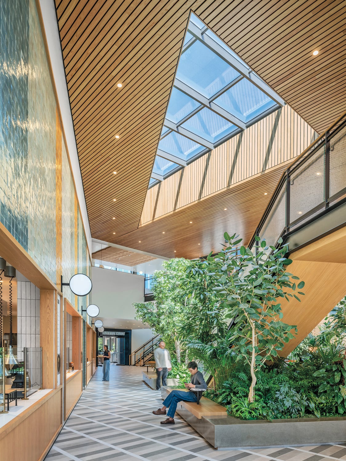 Zellige tile line a wall of serving stations in the Farewinds atrium, crowned by an acoustic wood-slat ceiling.